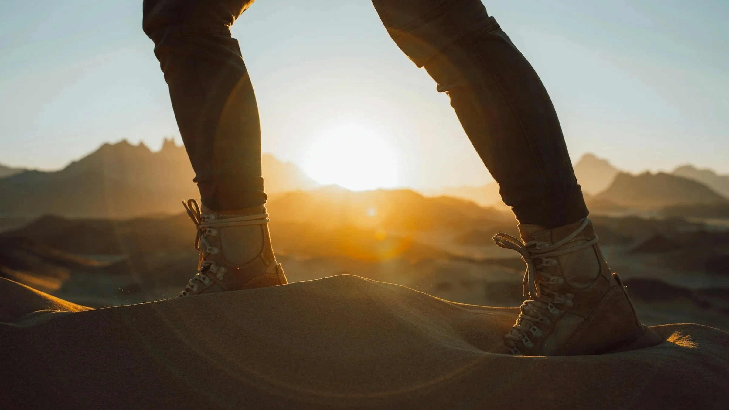 person in boots walking on sand dunes during a sunrise symbolizing overcoming obstacles working with Soul Journey Therapy & Coaching Services