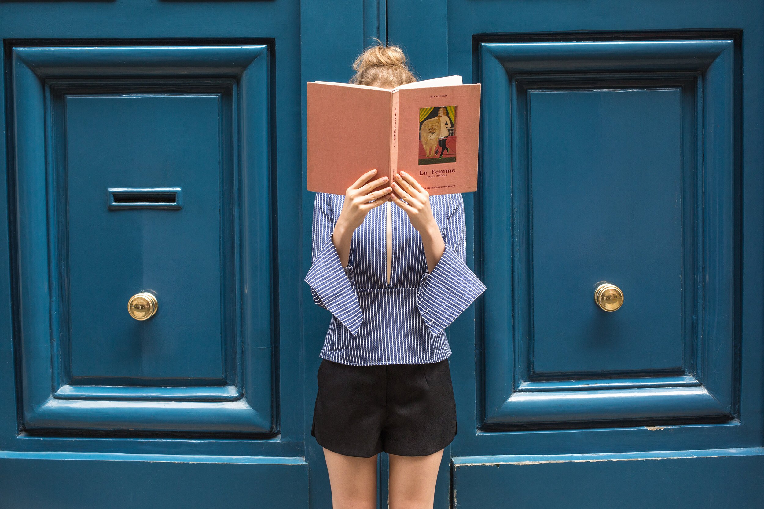 la femme book coversing face blue striped shirt playful paris street fashion.jpg