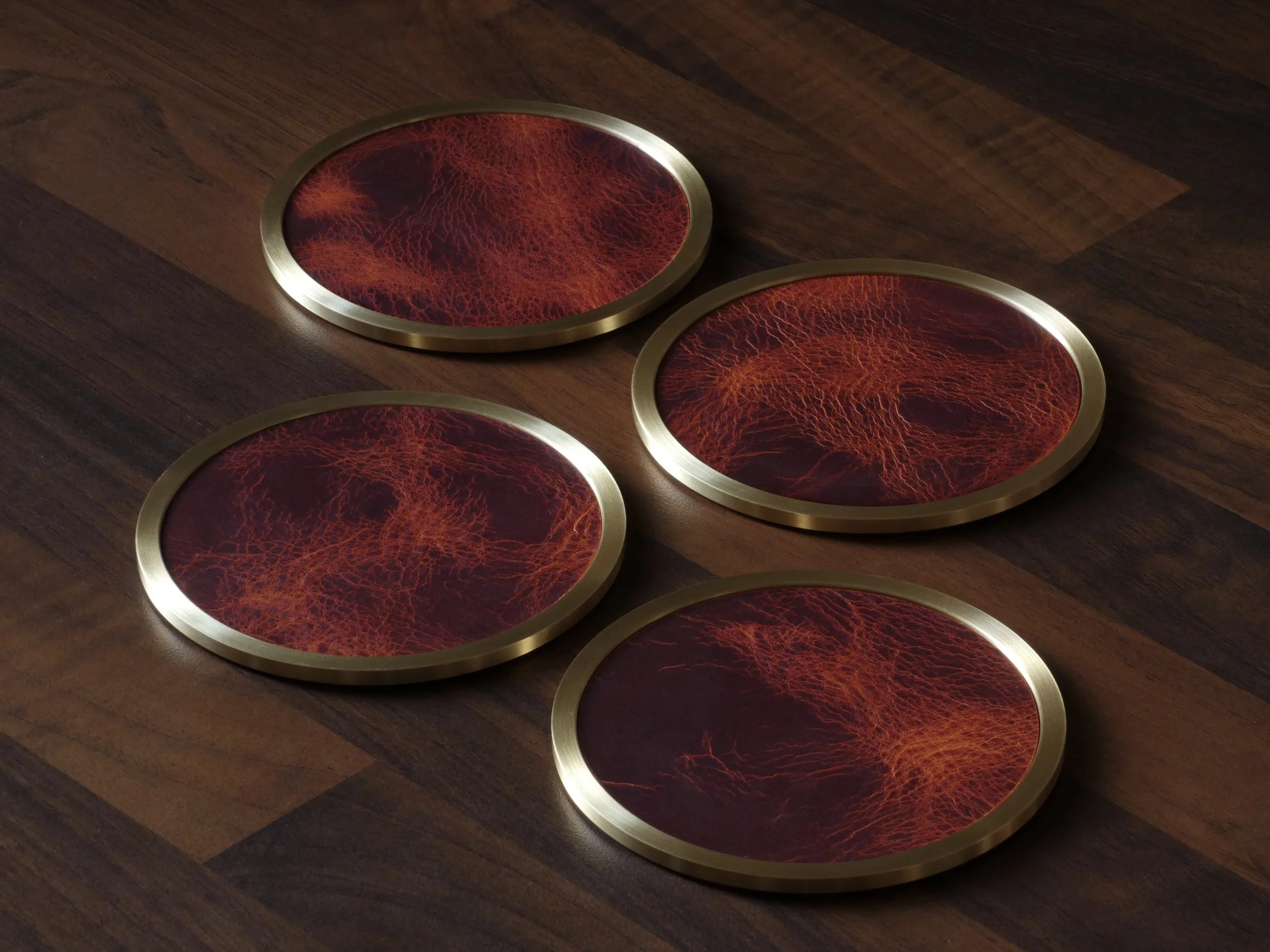 Four brass coasters inlaid with saddle tan leather