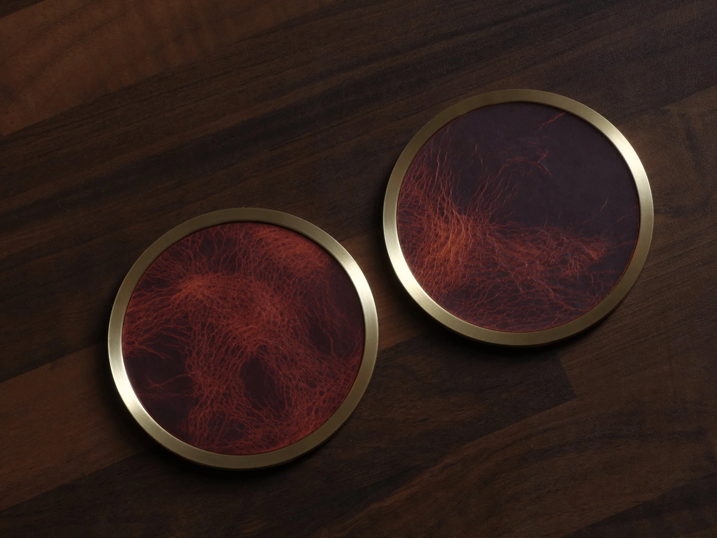 Two leather inlaid brass coasters