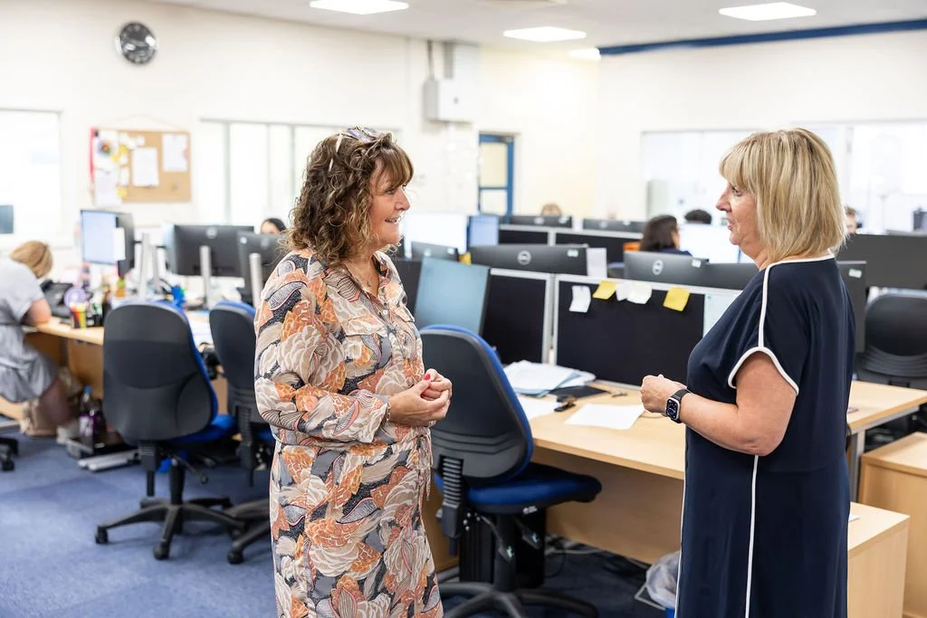 Two females stood chatting in the middle of an open plan law office in Nelson