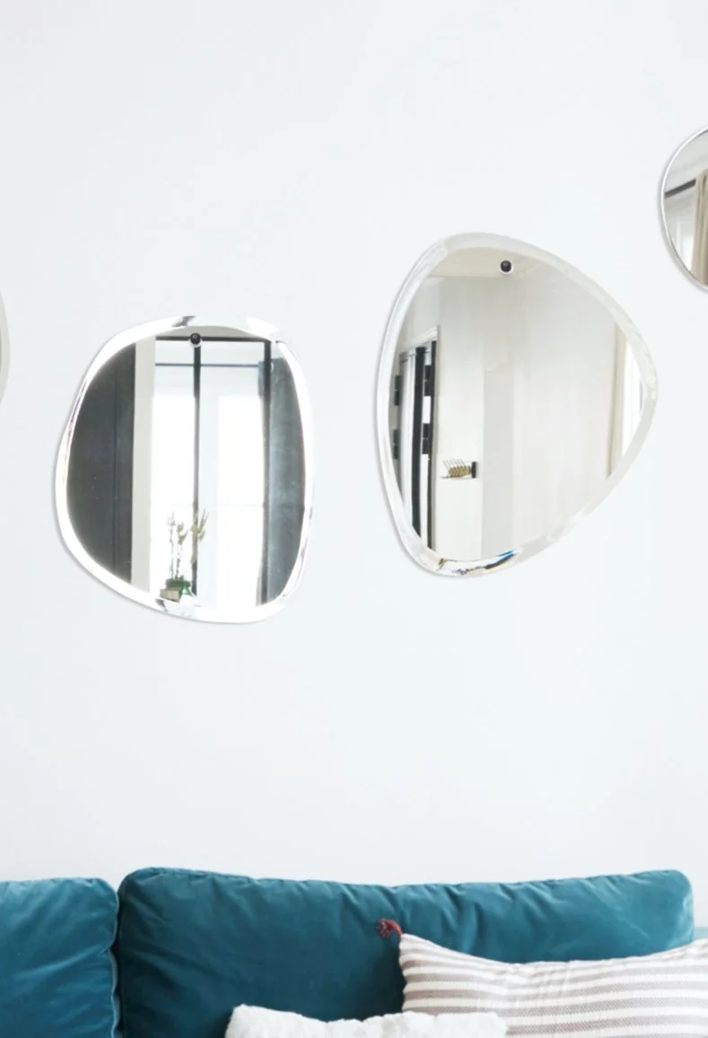 Miroirs ronds accrochés au mur au-dessus d'un canapé bleu avec un coussin rayé blanc et beige