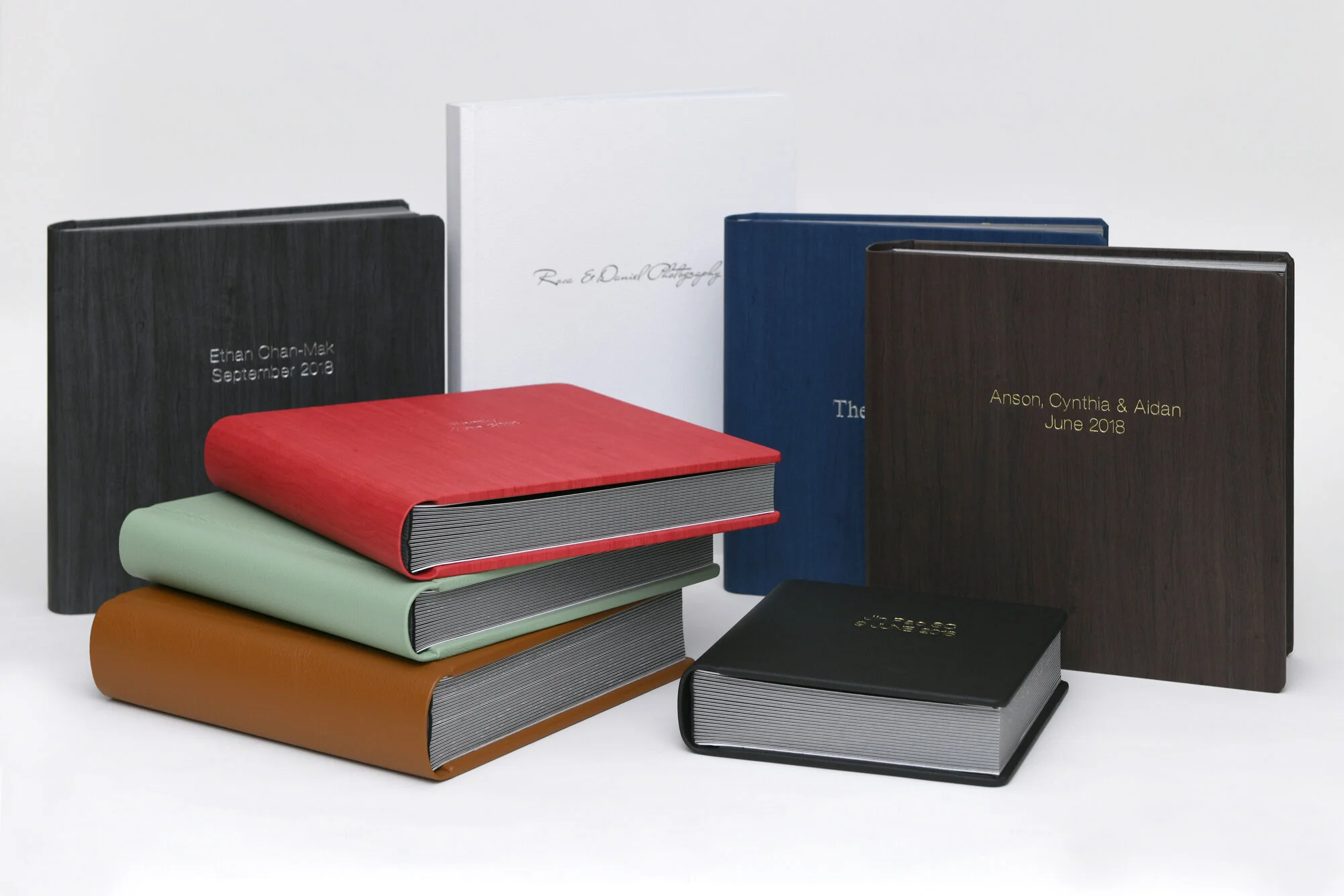 Stack of hardcover photo albums in various colors with embossed titles.