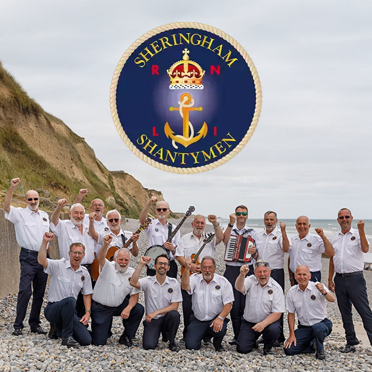 A group of men in white shirts and dark pants on a pebbled beach, holding musical instruments and raising fists in celebration, with cliffs and sea in the background, and a badge with a crown, an anchor, and the words "Sheringham Shantymen" and "RN" overhead.