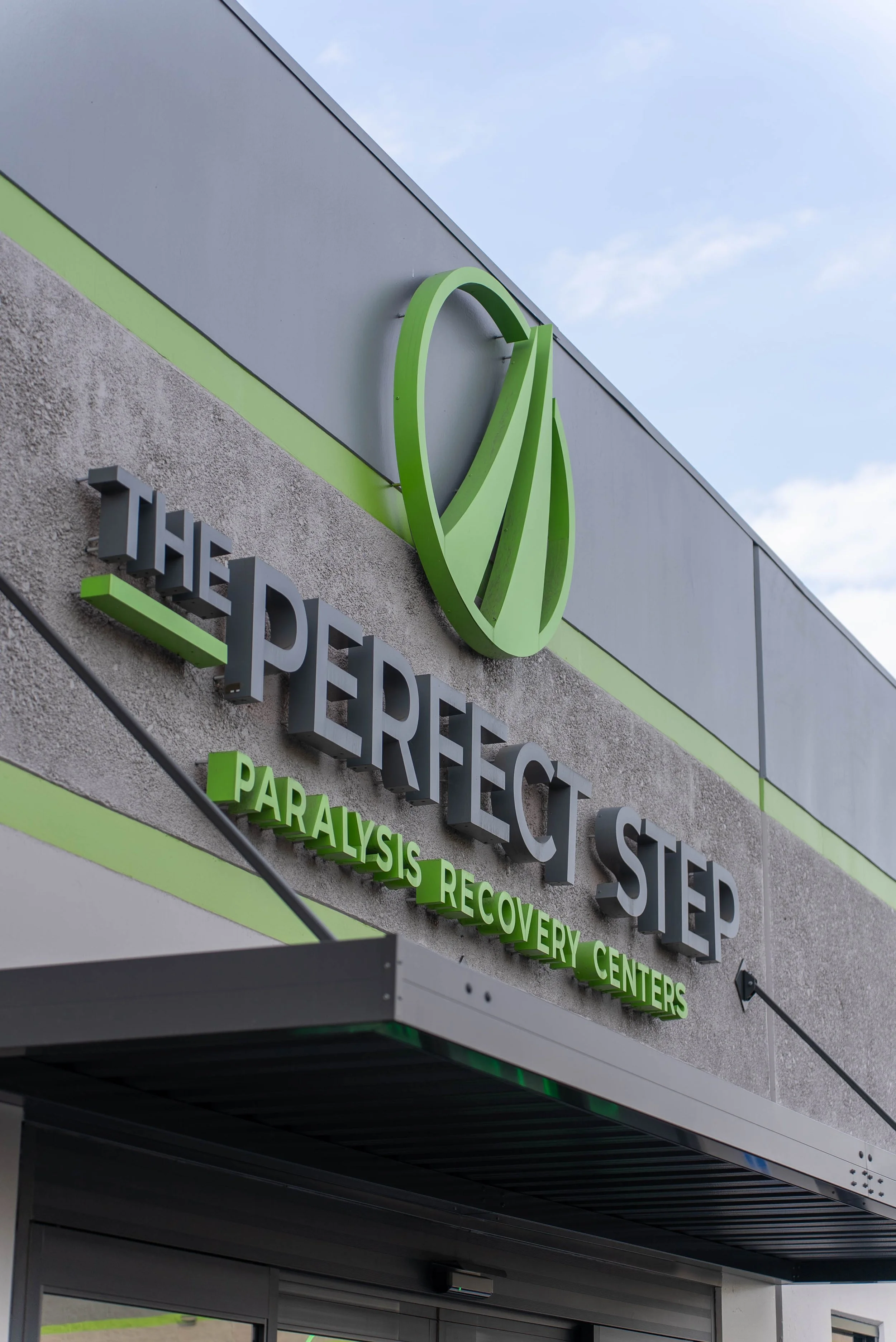 Sign for The Perfect Step Paralysis Recovery Centers with green logo on gray building