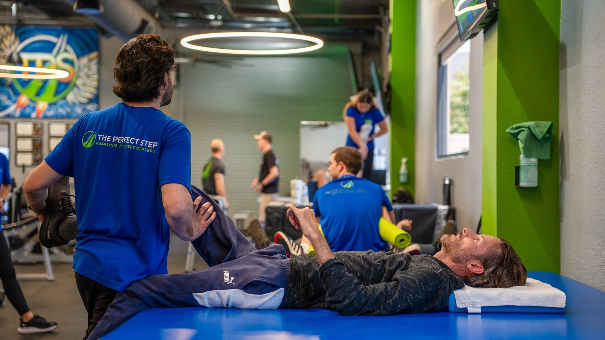 A man lying on a treatment table receiving physical therapy from a physiotherapist at a rehabilitation center.