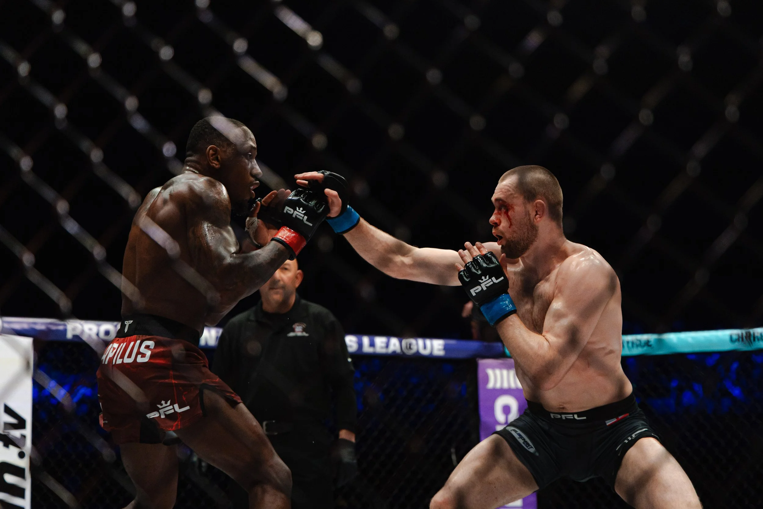Twee vechters in een ring, die elkaar slaan tijdens een MMA-gevecht, met een wedstrijdnet en een scheidsrechter op de achtergrond.