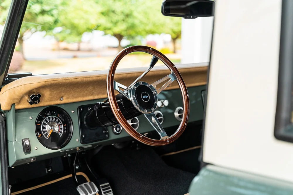 Wood steering wheel, classic gauges and leather dash inside a HighLine Classic Bronco