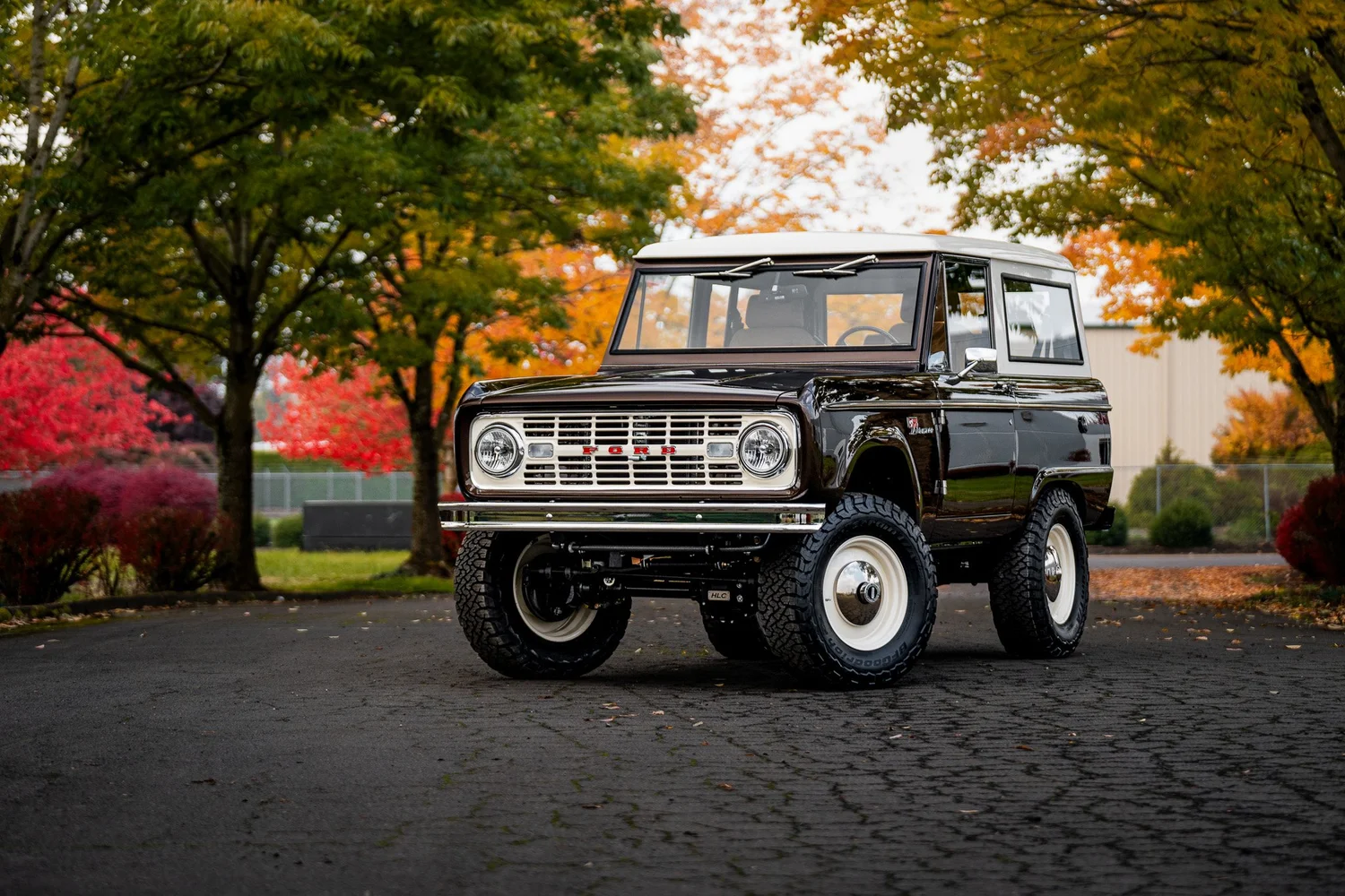 HighLine Classic Bronco with a white hardtop parked beneath autumn trees