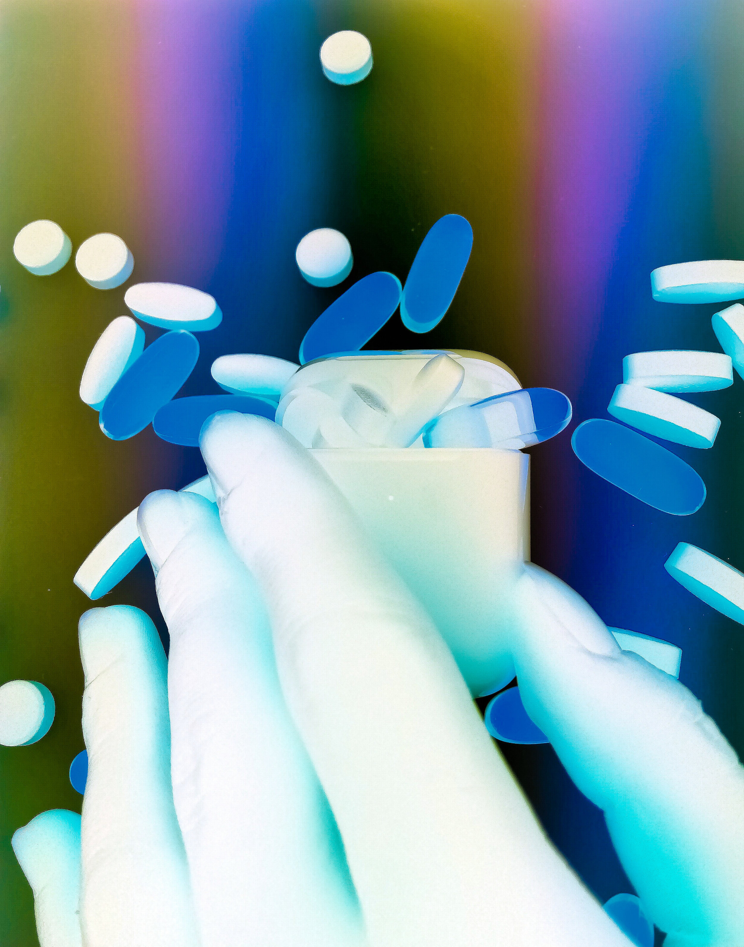 Inverted photograph of hand holding apple air pods. Pills. Psychedelic music. Hallucinogen. Oil slick rainbow effect. Abstract.