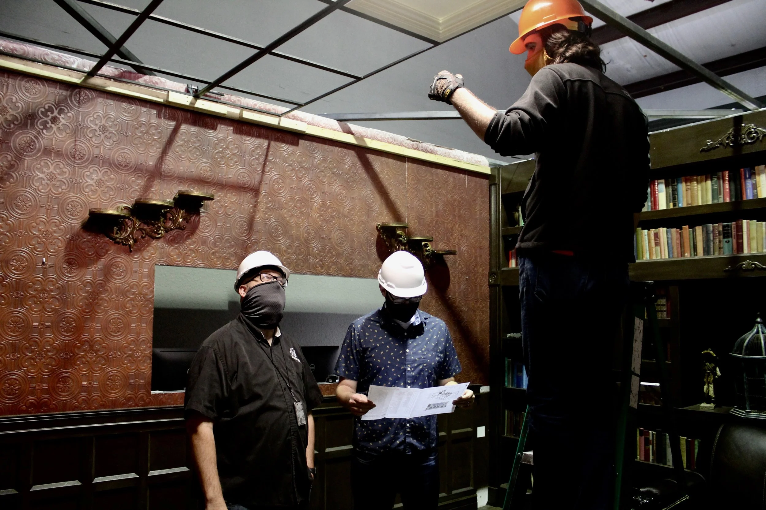 Three men constructing an indoor haunted house set