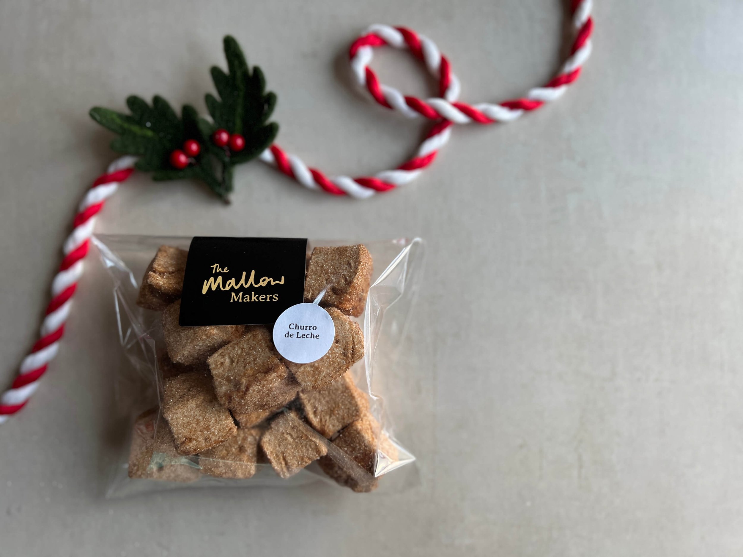 Looking-down-on-packet-of-churru-de-leche-marshmallow-bites-coated-in-cinnamon-sugar-with-christmas-ribbon.jpg