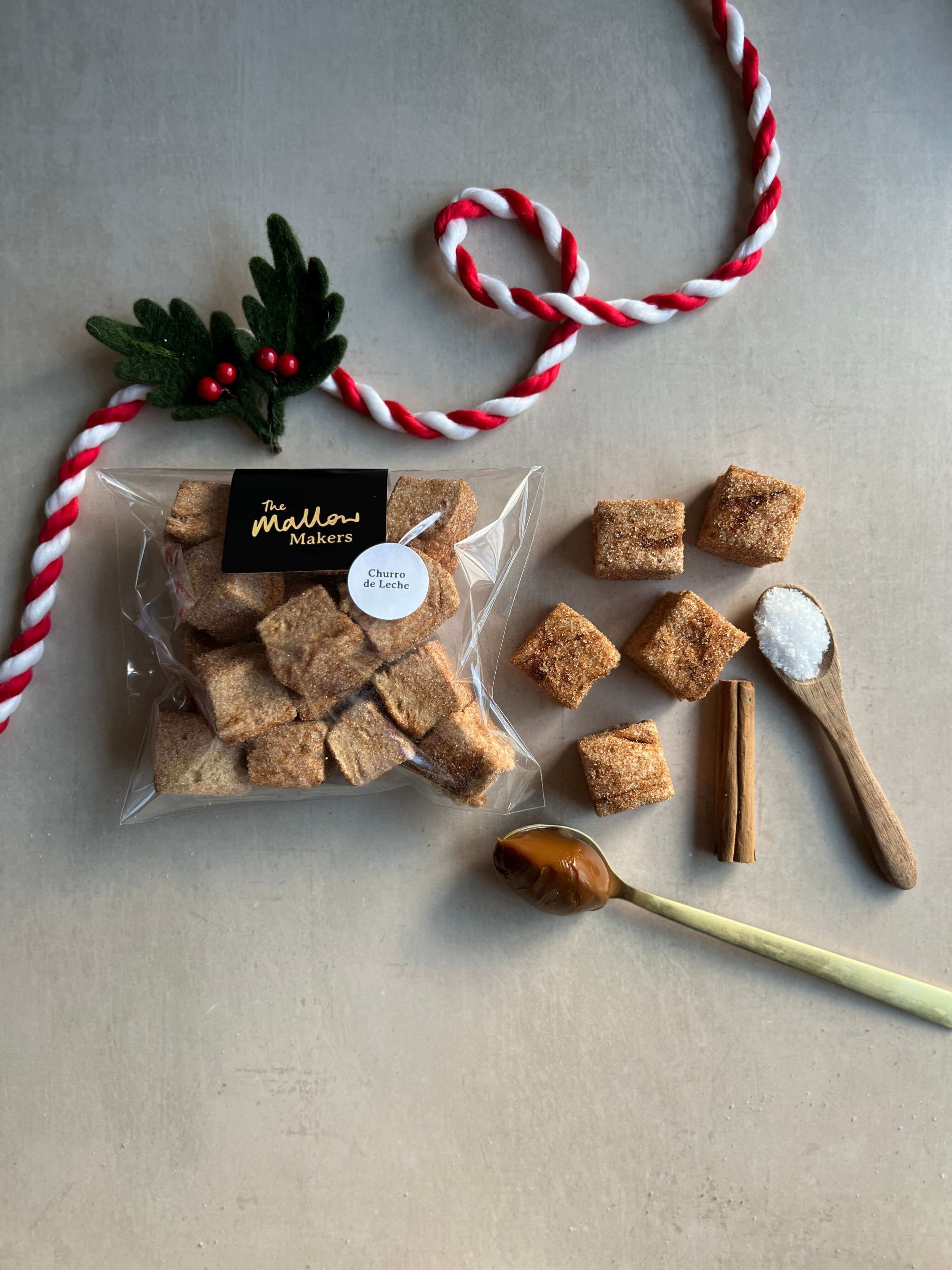looking-down-on-packet-of-churro-handmade-marshmallows-with-spoons-of-dulce-de-leche-and-salt-and-cinnamon-stick-with-christmas-ribbon.jpg