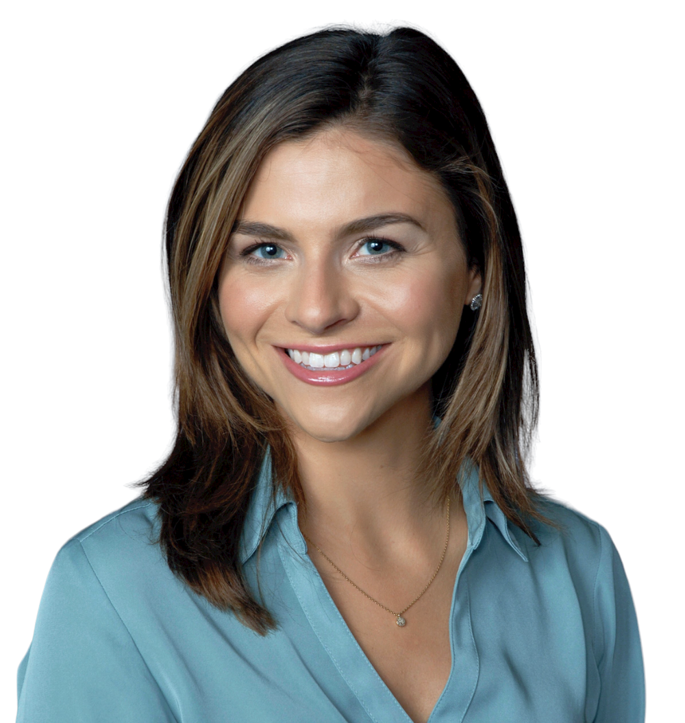 A young white woman with shoulder-length brown hair and blue eyes smiles into the camera with her head tilted to the left. She is wearing a blue collared shirt and small pendant necklace.