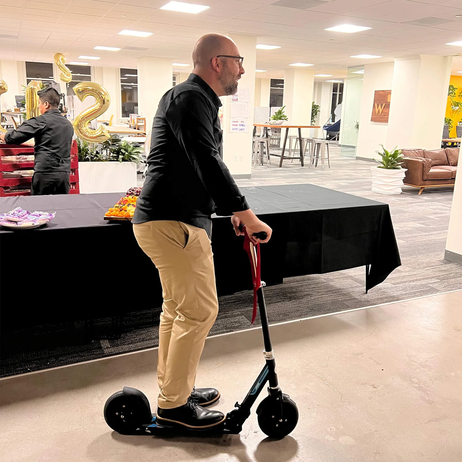 Brian Peters Rides A Scooter In The Woodblock Office