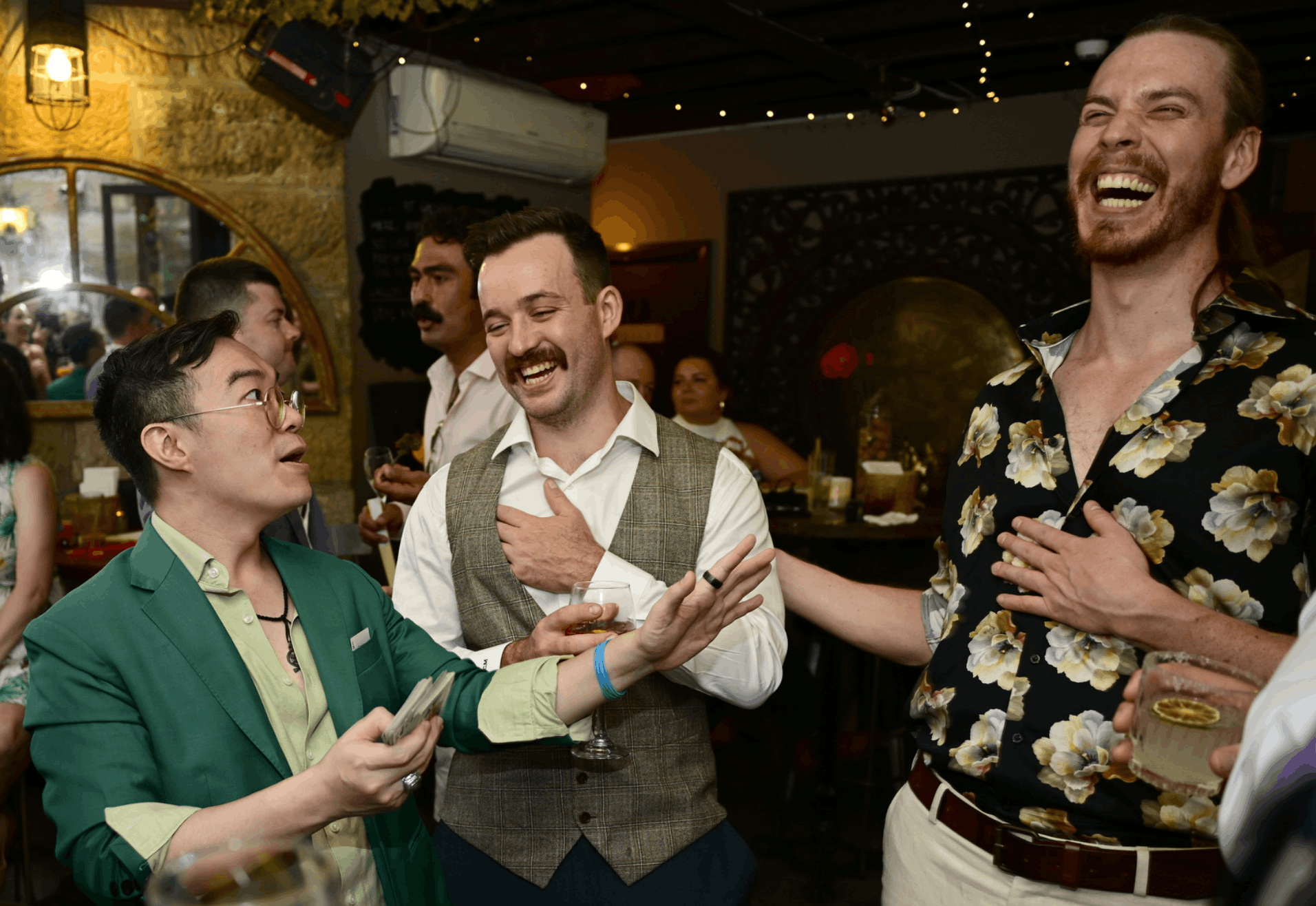 Group of diverse people at an outdoor event, watching a magician, by the water, shaking hands, smiling, and taking photos, with the Sydney Opera House in the background.