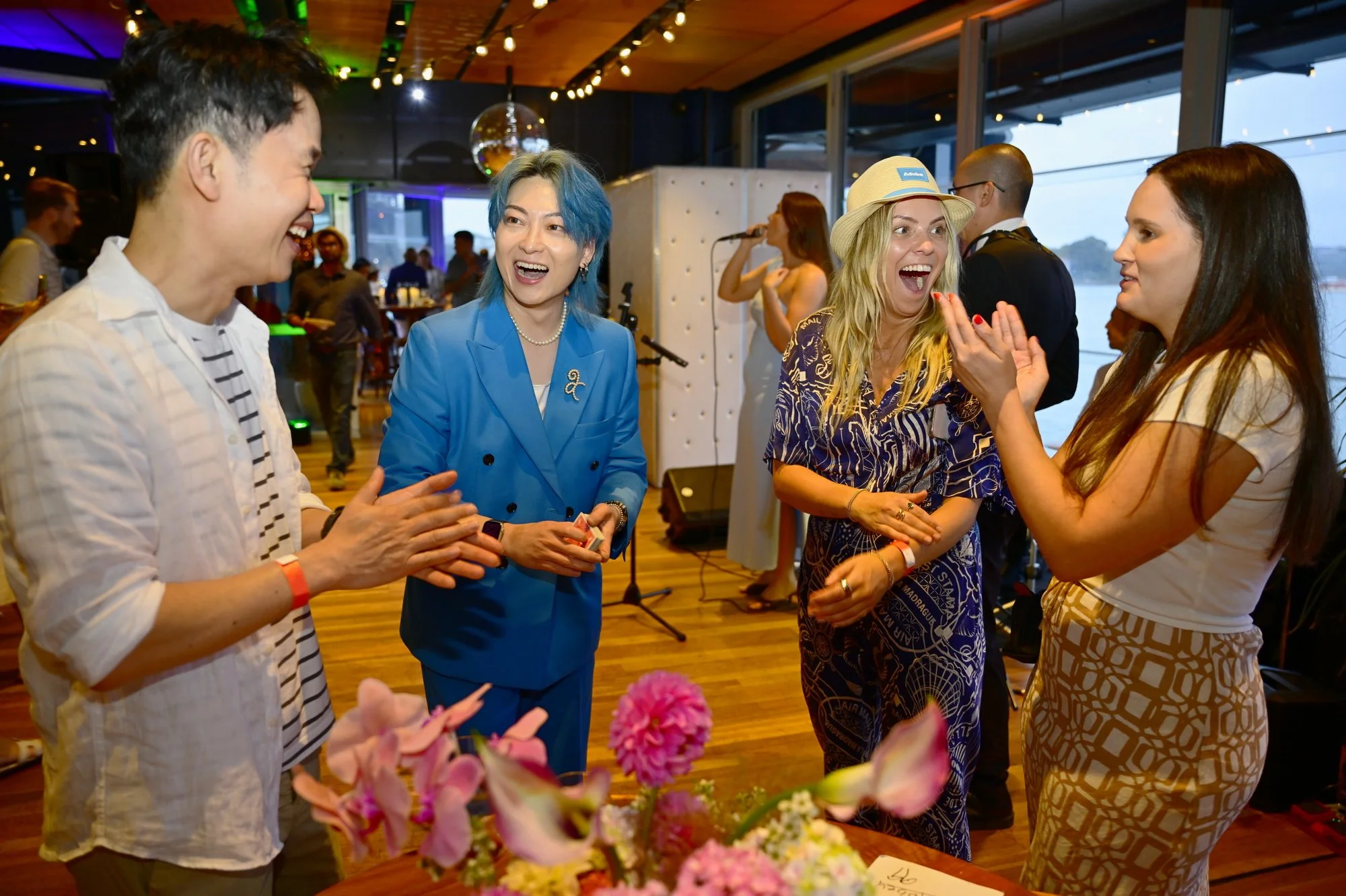 Group of friends laughing and having fun at a formal event or celebration, whilst watching a magician from Sydney.