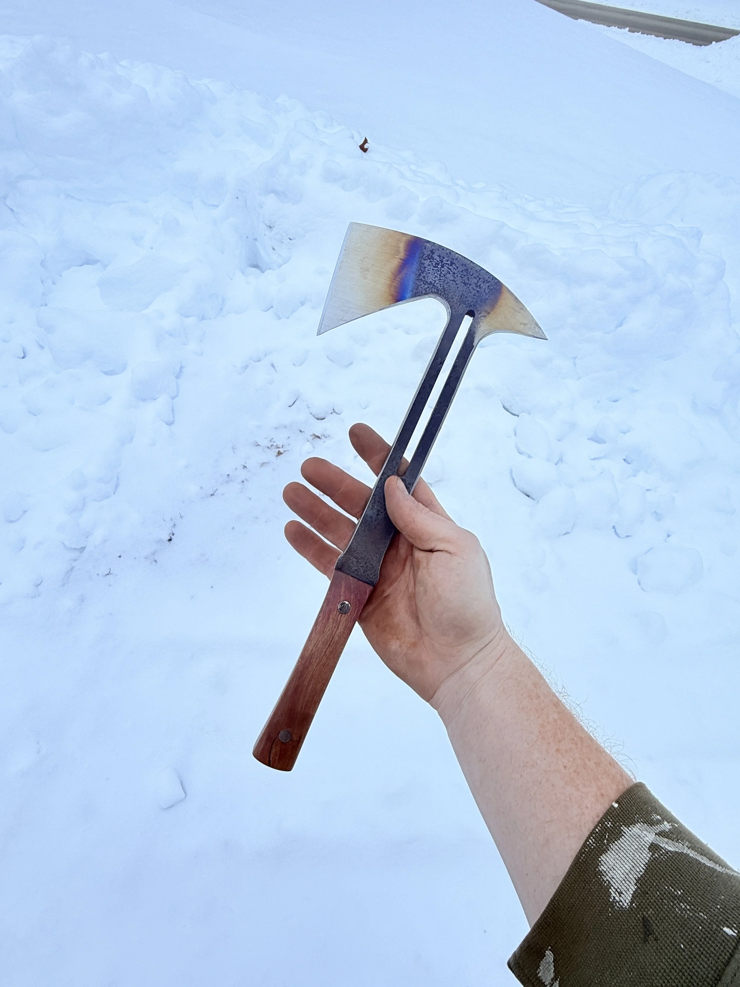 A person holding an axe in a snowy outdoor setting.