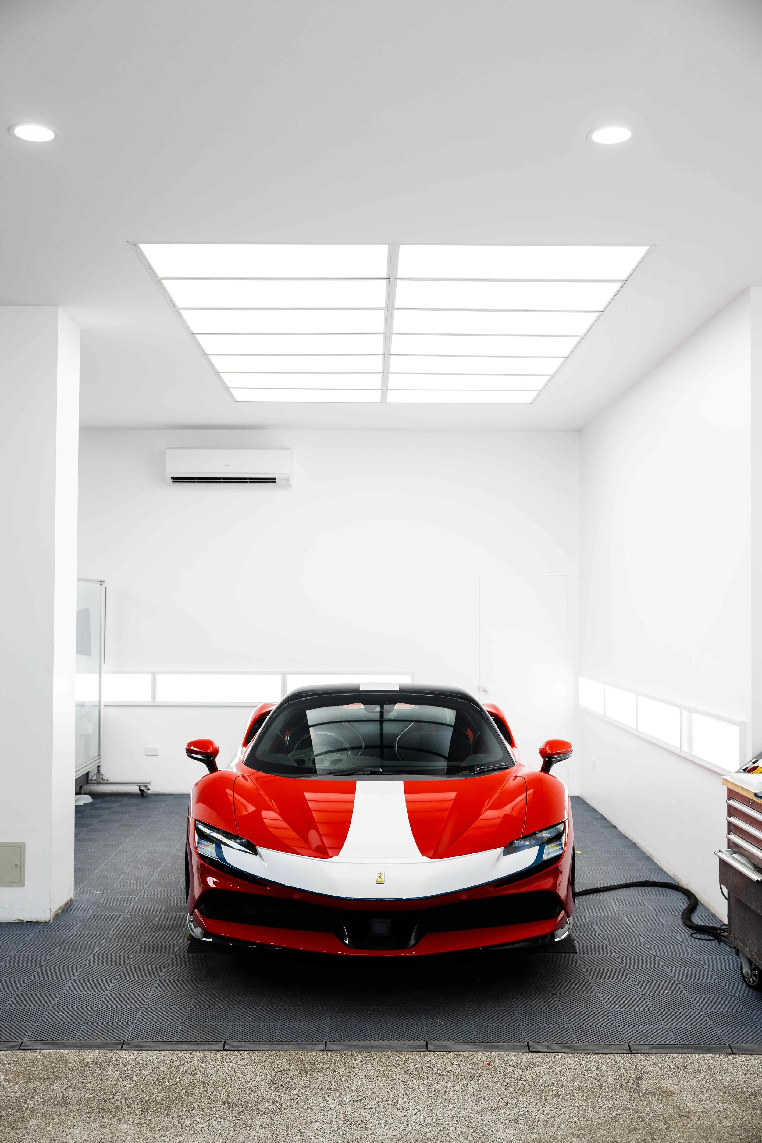Red Ferrari SF90 Spyder wide front view in studio with white stripe and XPEL Paint Protection Film in Sydney