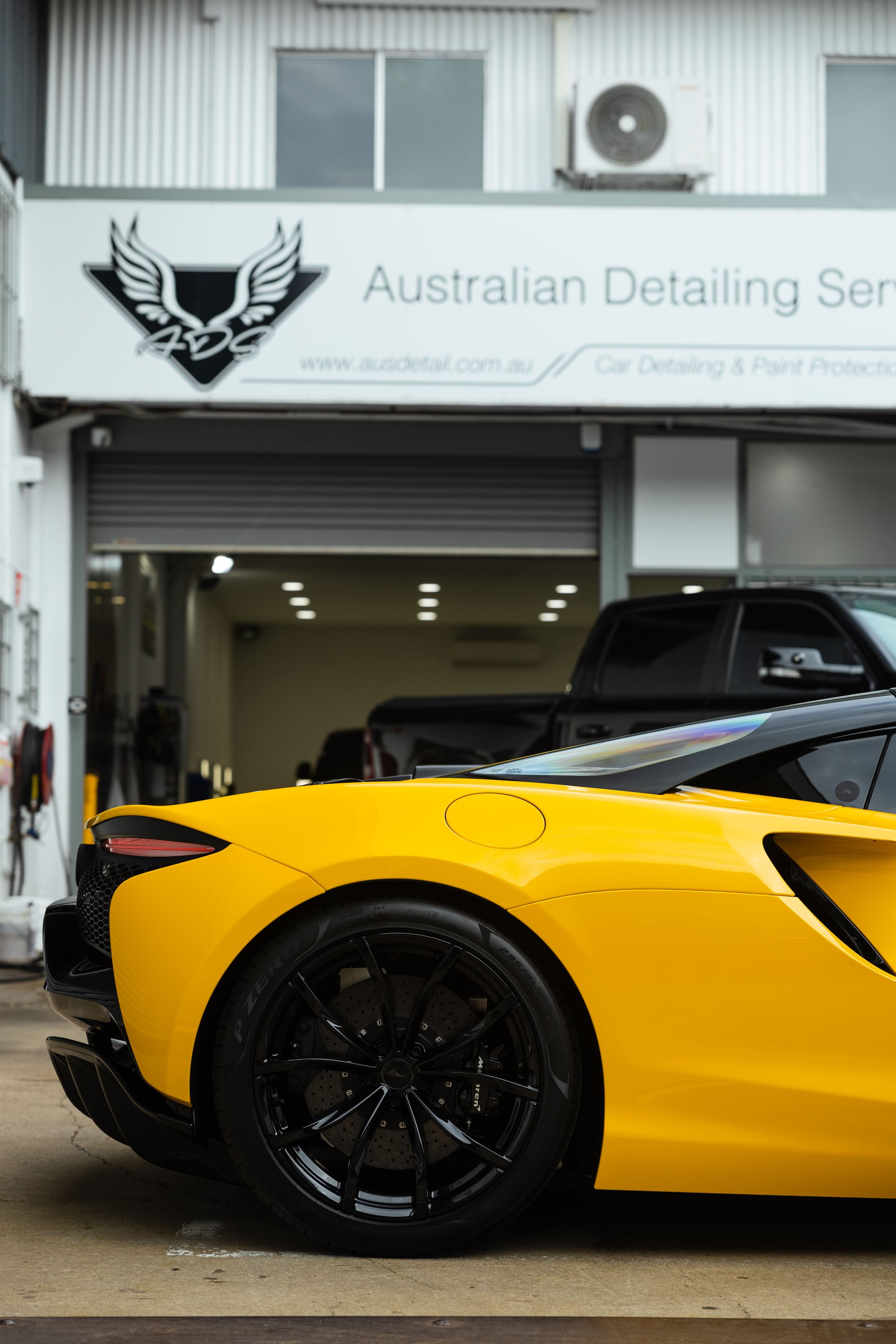 Yellow McLaren Artura rear quarter outside ADS workshop with full PPF protection in Mona Vale
