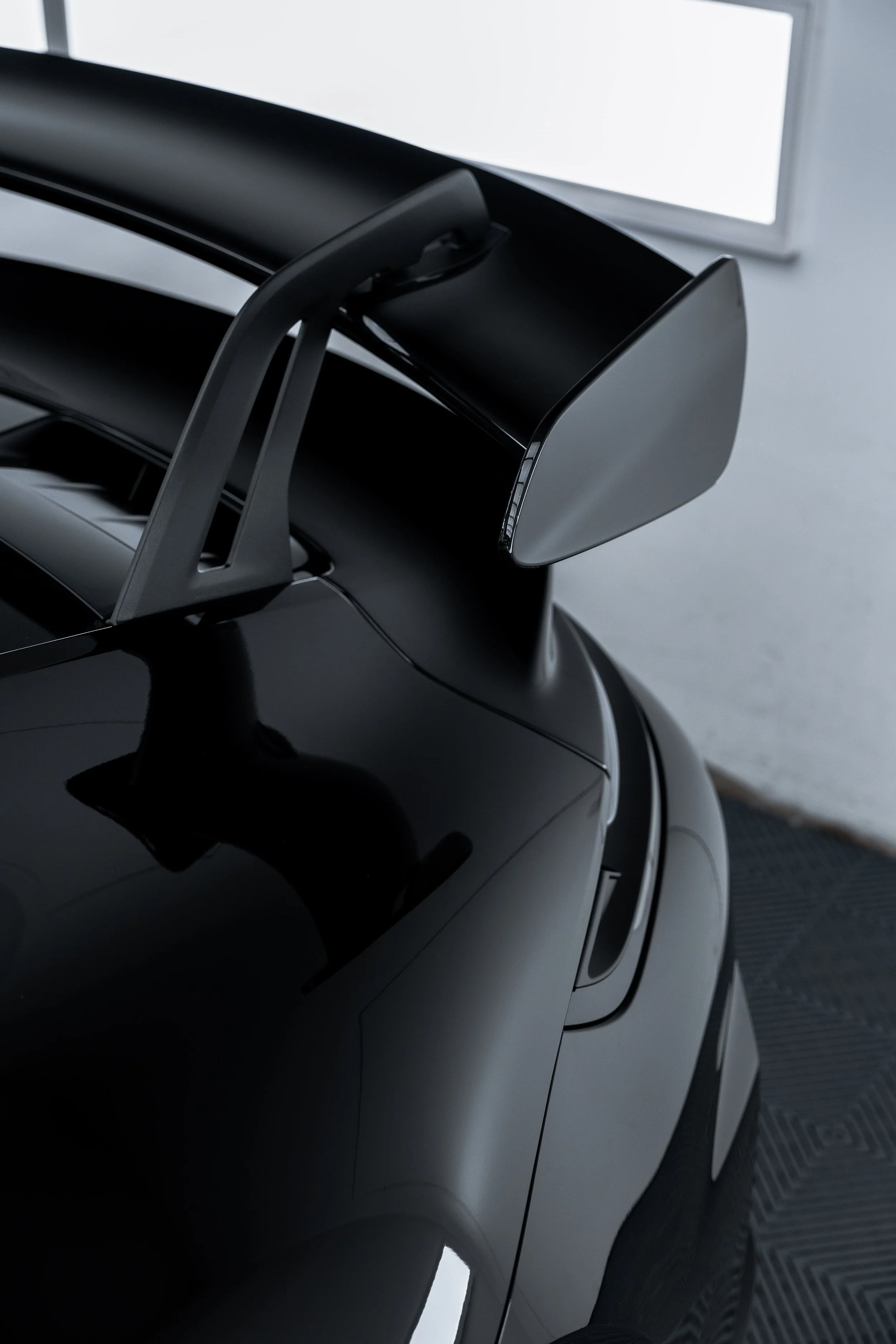 Close-up of Porsche 911 GT3 rear wing and sculpted rear quarter panel in a detailing studio