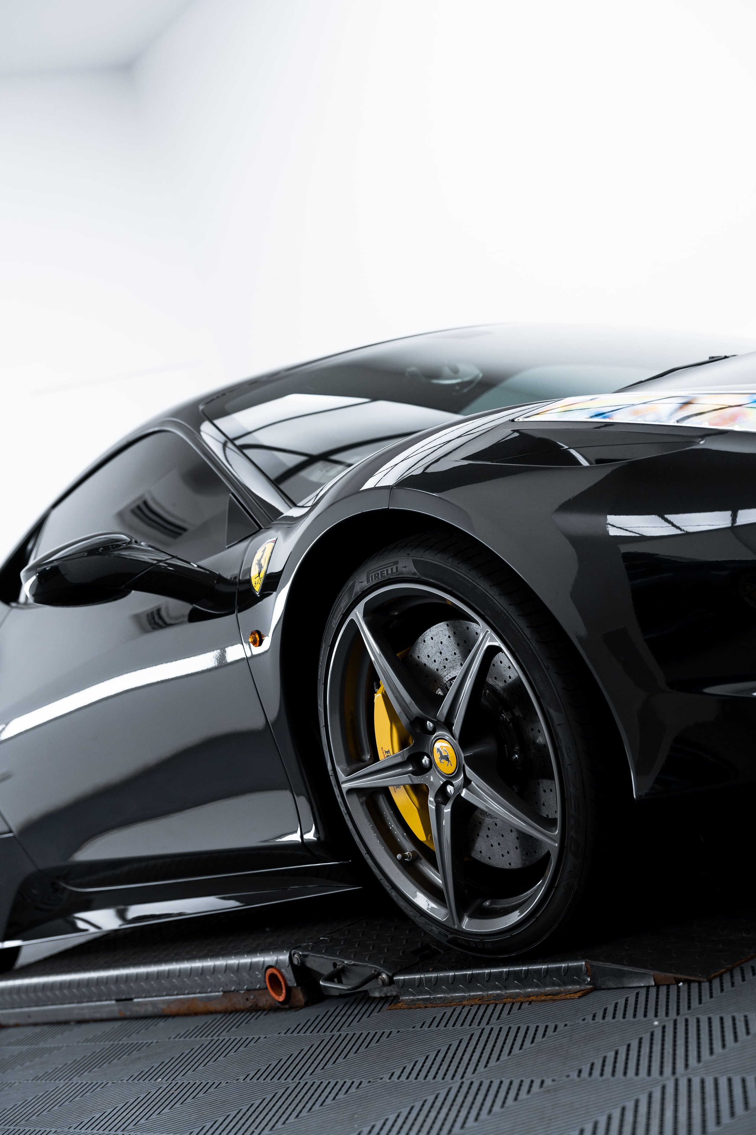 Front quarter view of black Ferrari 458 with yellow brake calipers and alloy wheel, detailed and protected with PPF by ADS