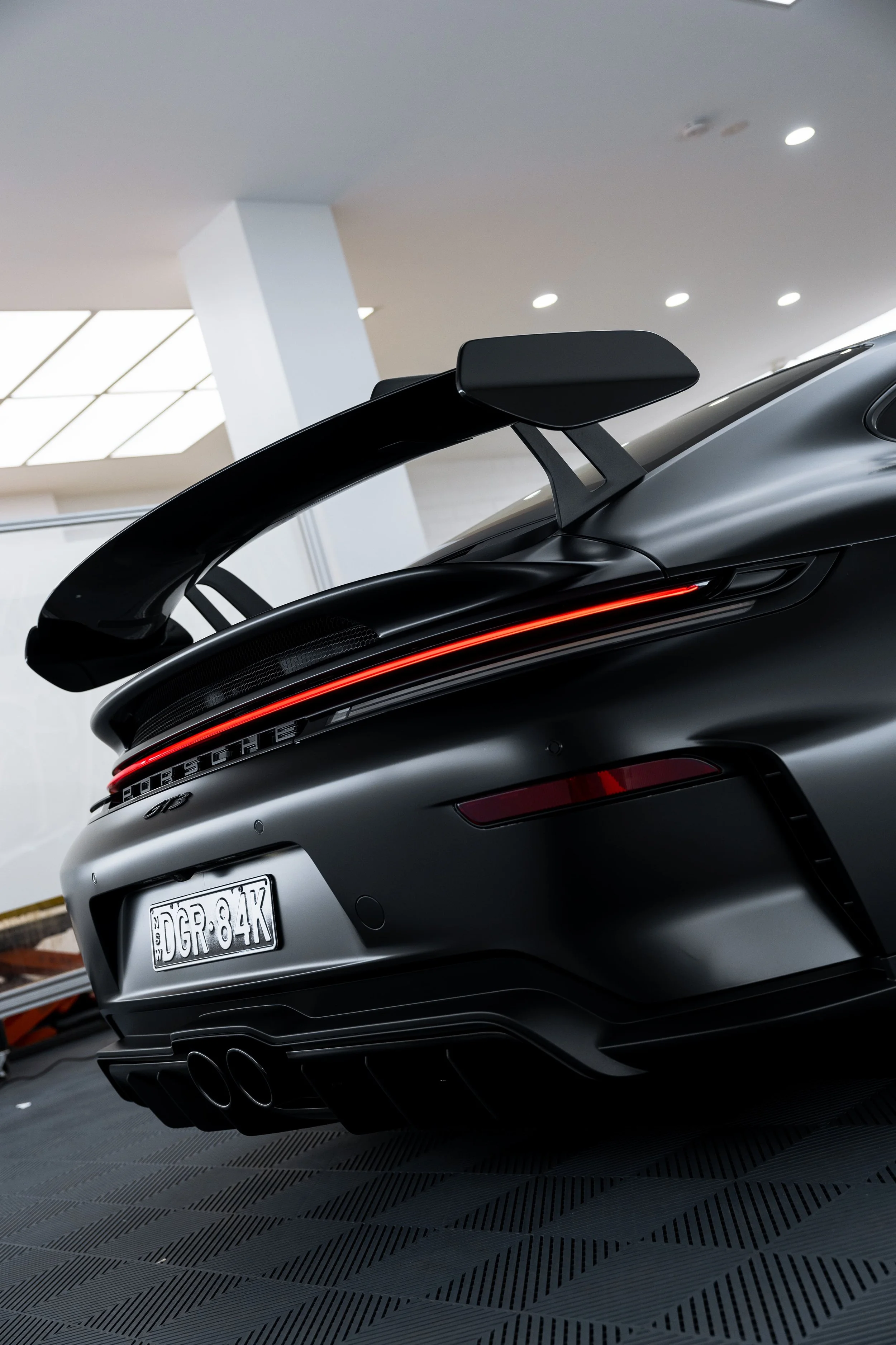 Rear view of black Porsche 911 GT3 with matte PPF finish, LED light bar and rear wing by ADS in Mona Vale