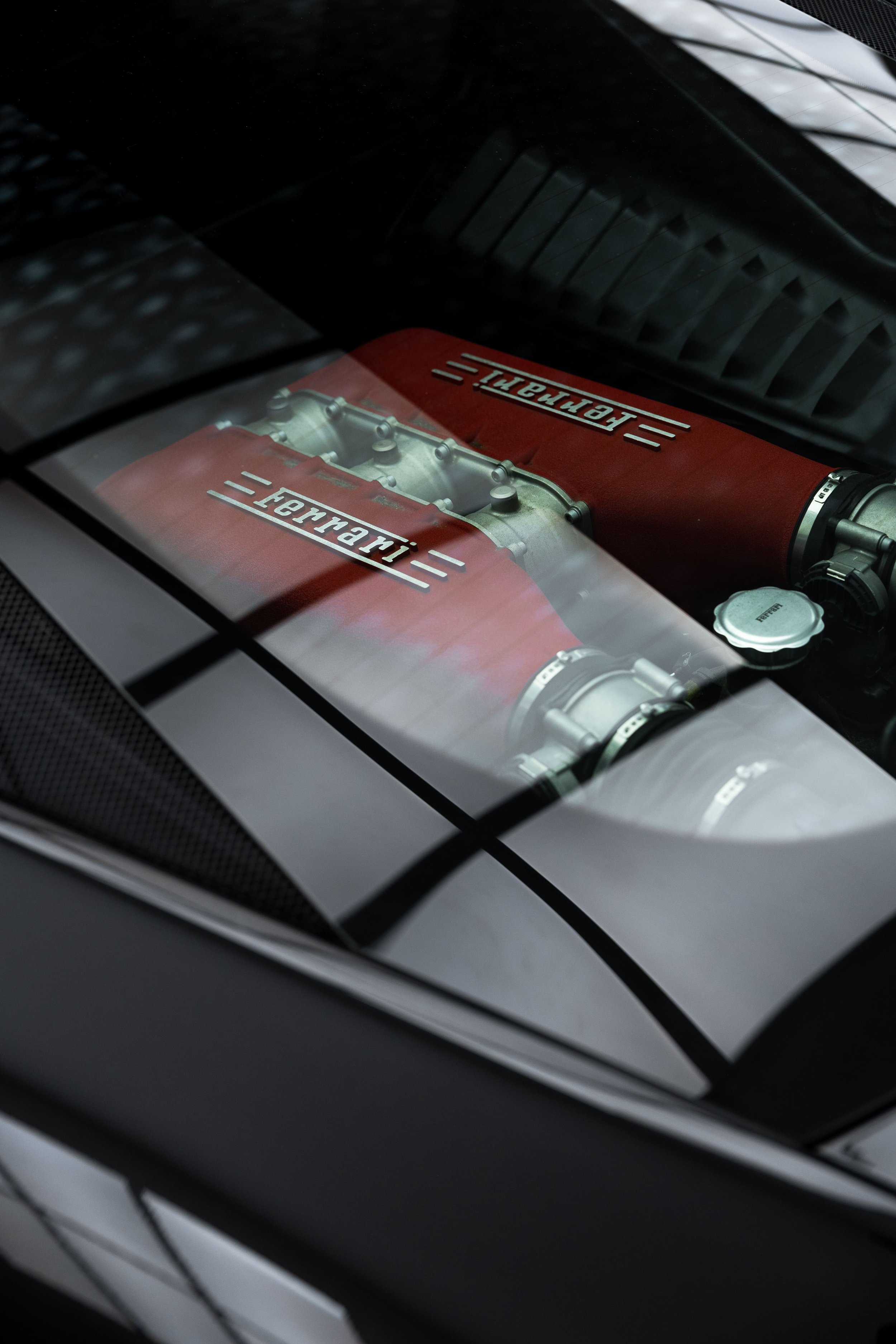 Close-up of Ferrari 458 engine bay with red intake covers visible through rear glass, showcasing performance detailing and PPF protection by ADS