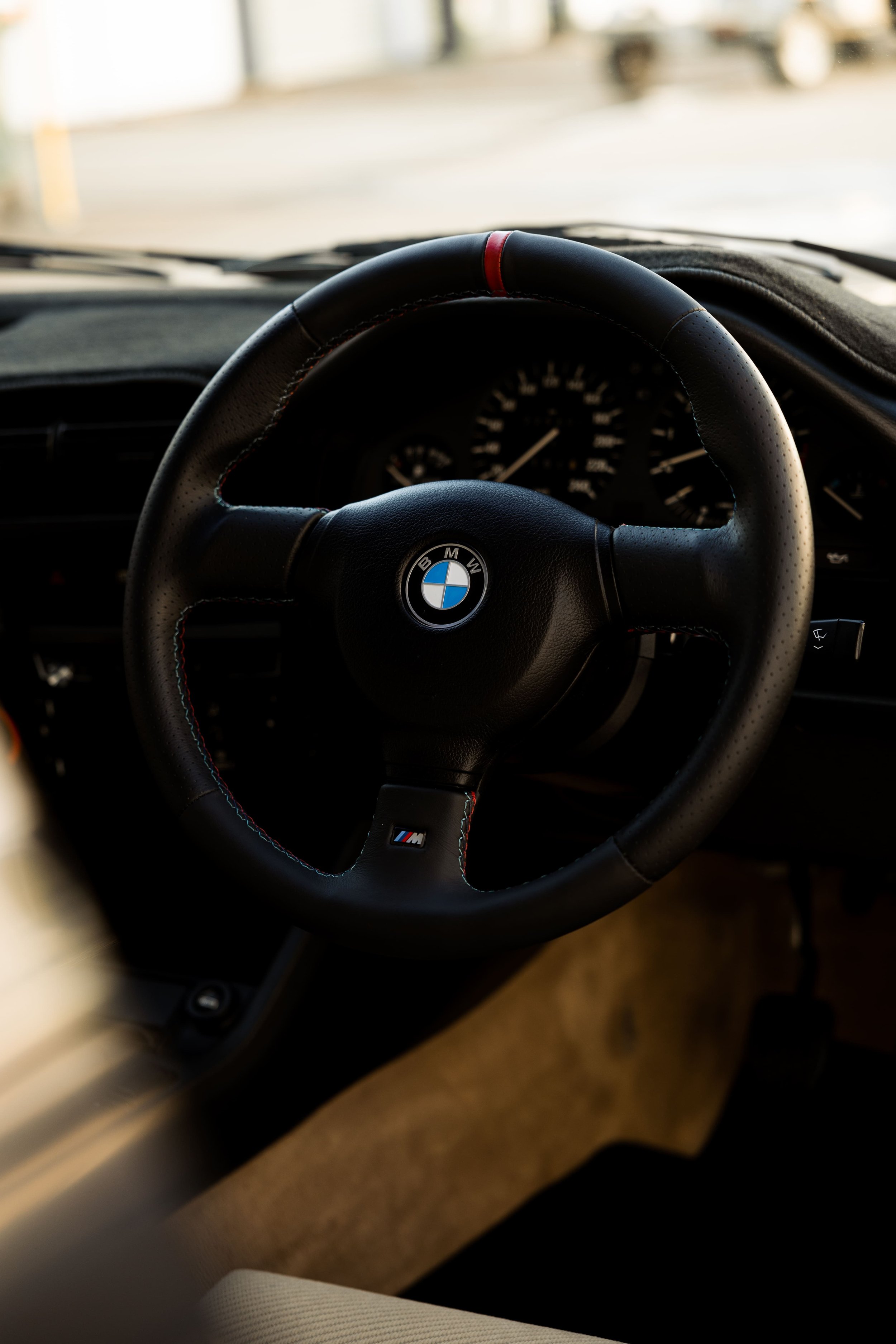BMW E30 interior steering wheel with BMW badge and classic analog gauges, showcasing driver-focused design and restored finish by Australian Detailing Services Sydney