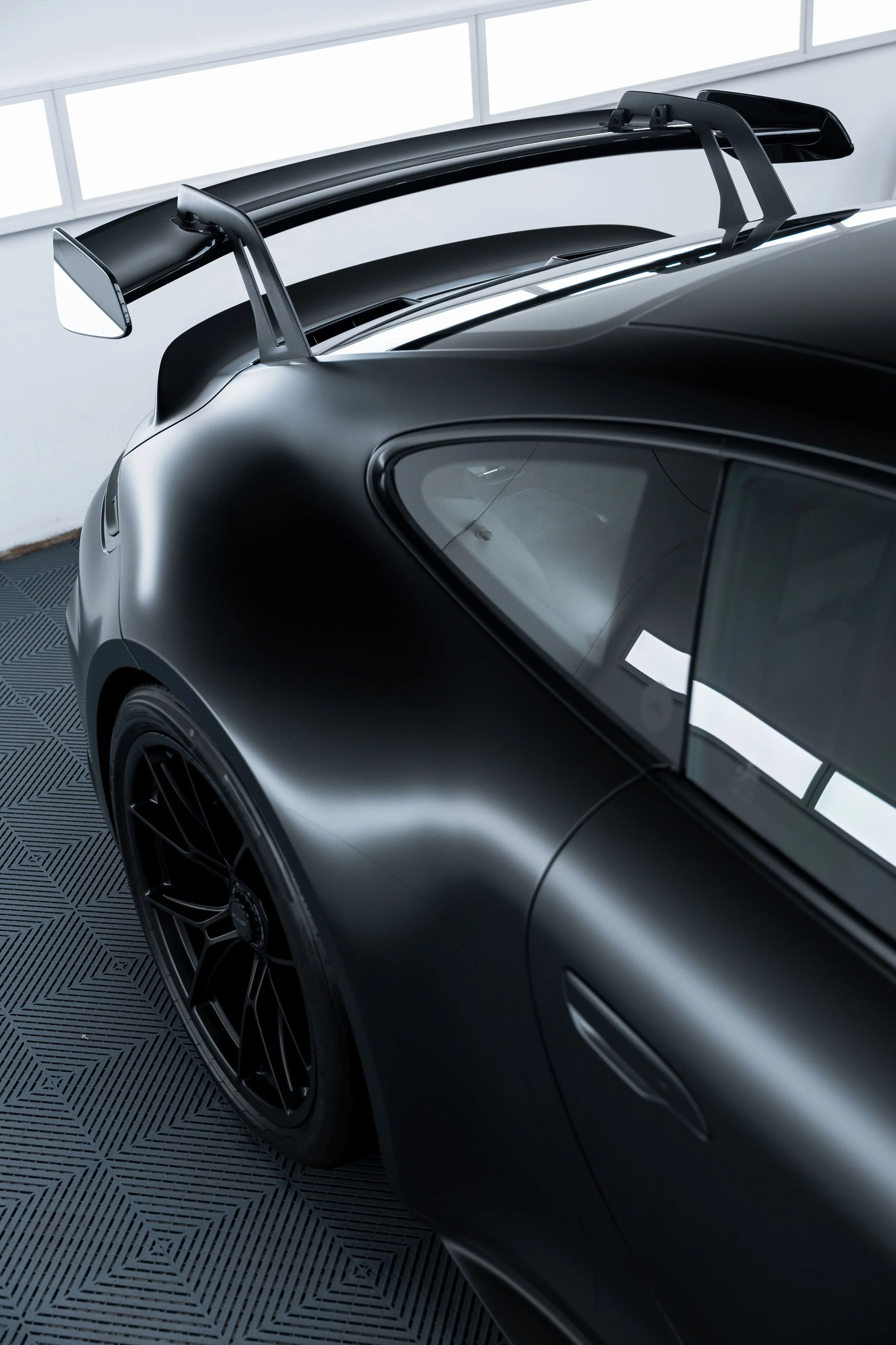 Rear quarter view of black Porsche 911 GT3 with matte PPF finish and carbon rear wing by ADS in Mona Vale