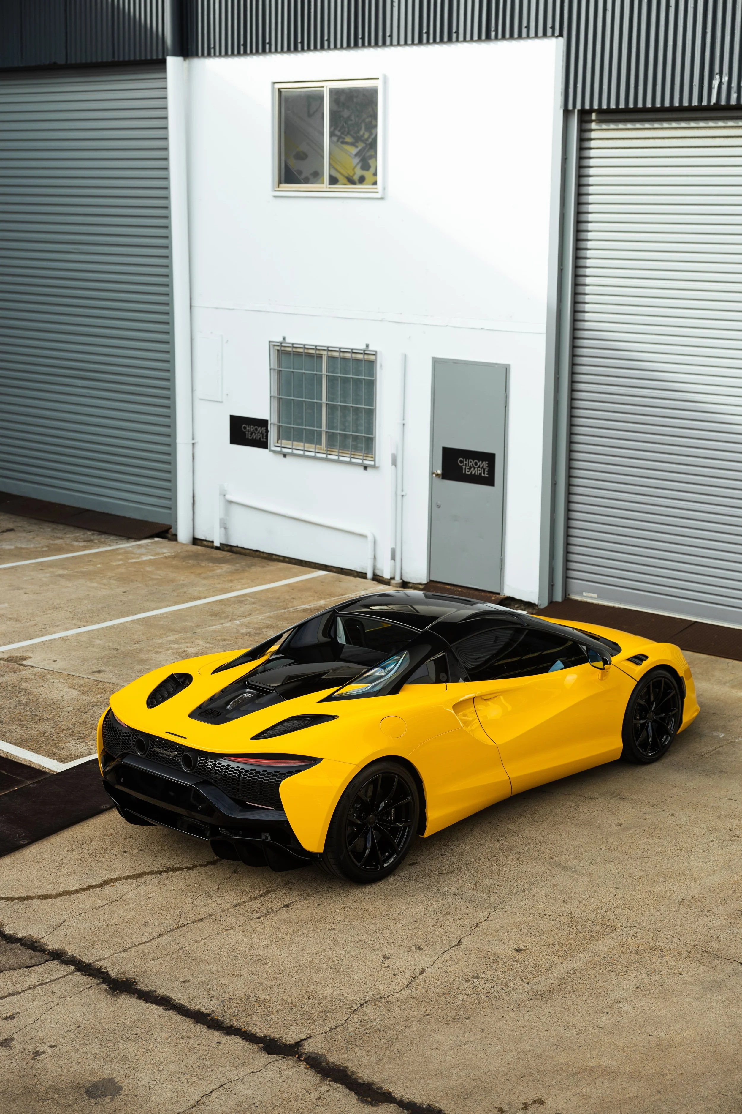 Yellow McLaren Artura rear three-quarter view outside ADS workshop with full PPF protection in Mona Vale