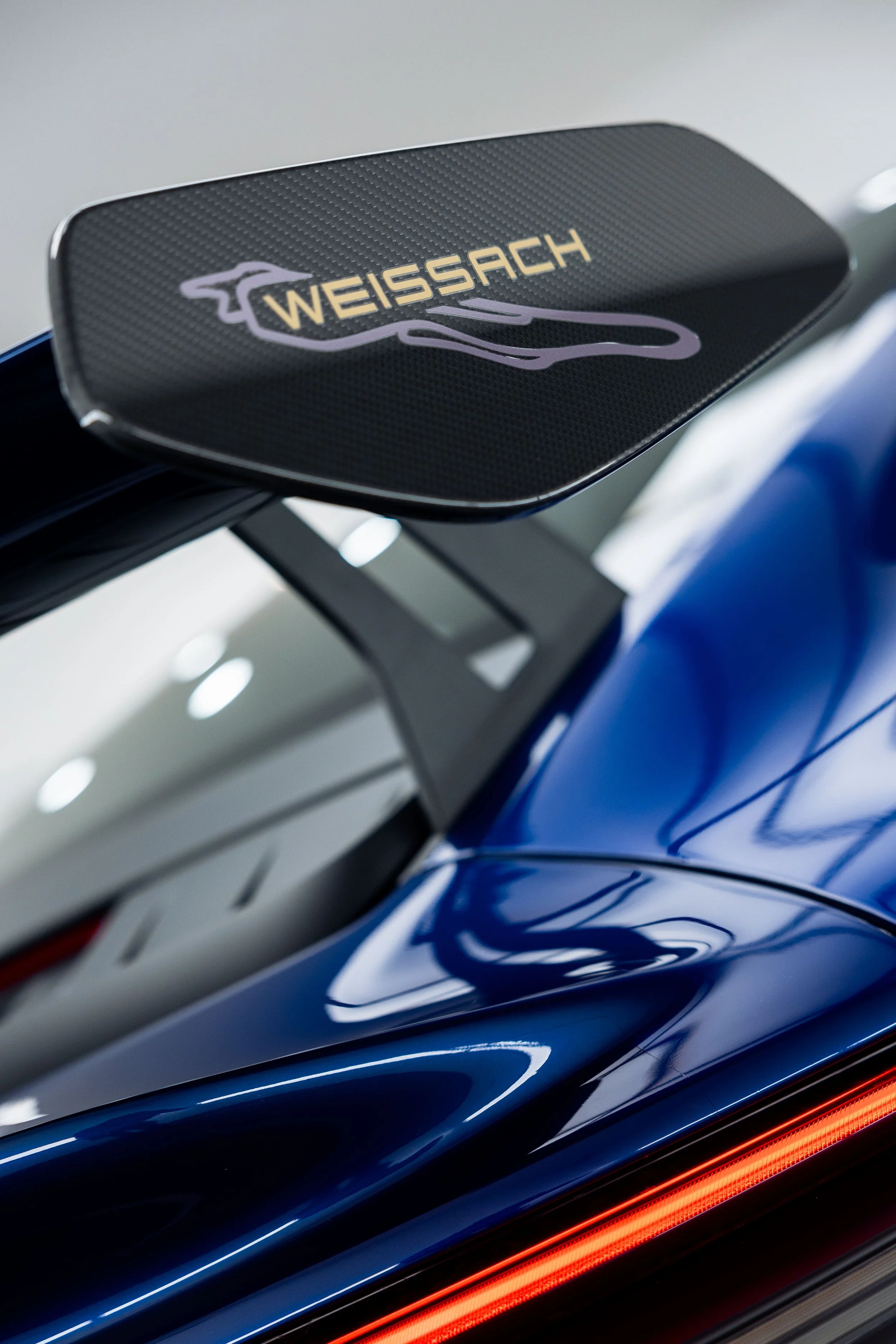 Close-up of Porsche 911 GT3 Weissach package carbon fibre rear wing with blue paint and LED tail light detail