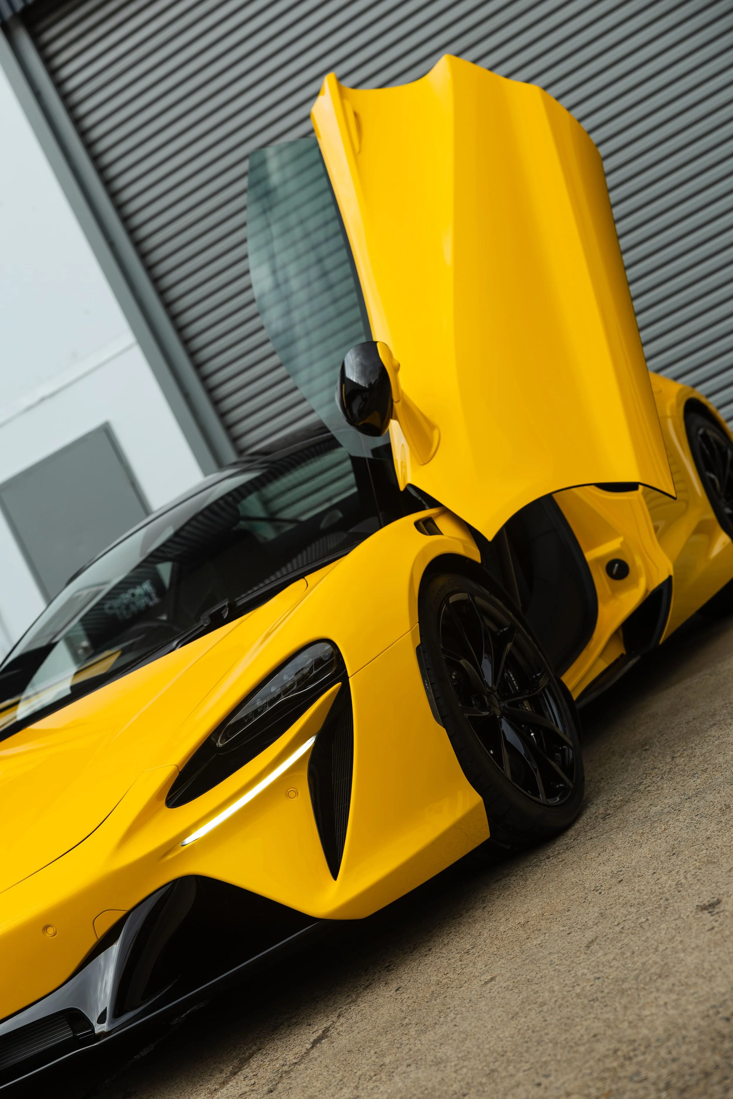 Yellow McLaren Artura front three-quarter view with door open and full PPF protection by ADS in Mona Vale