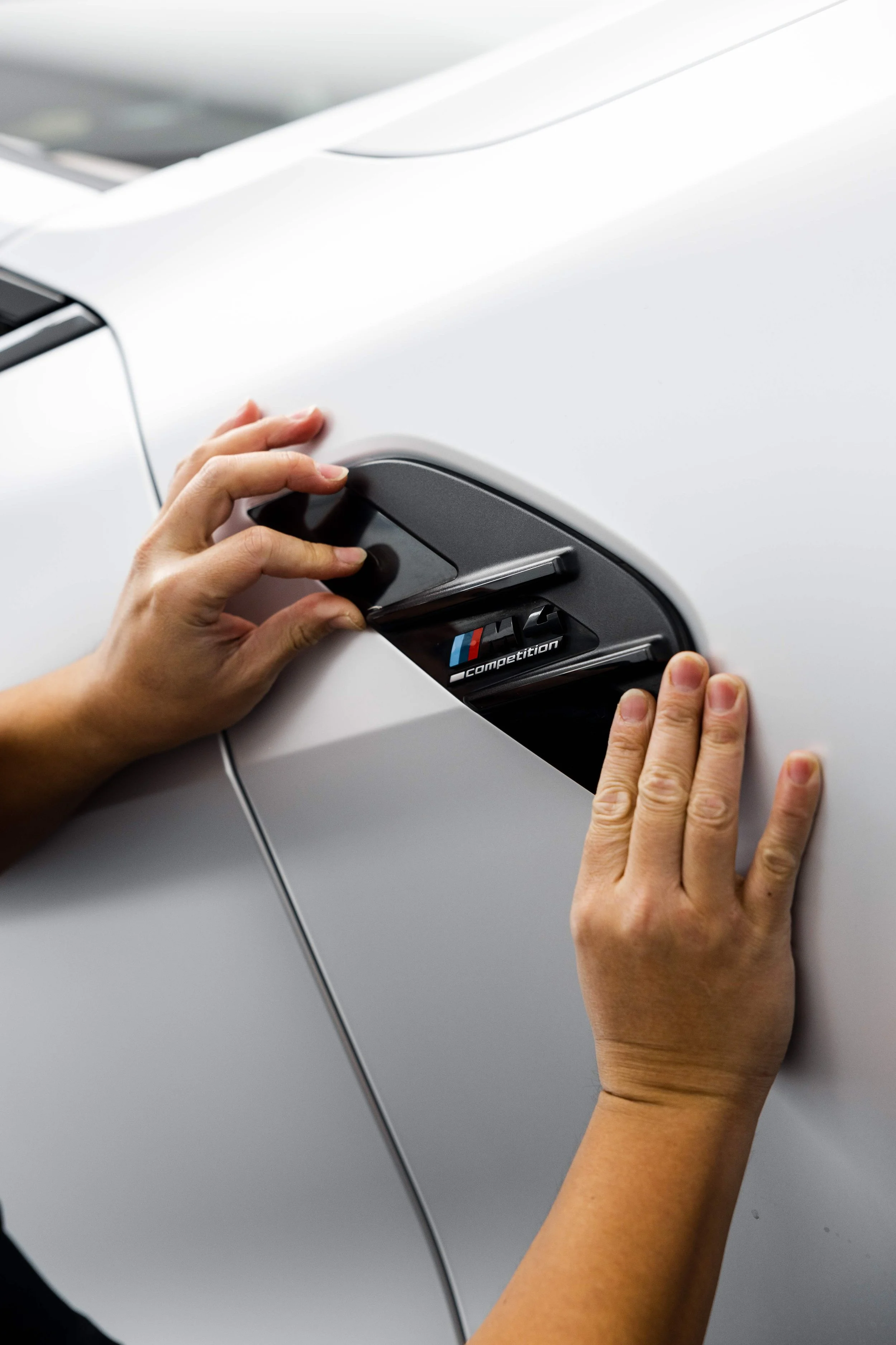 ADS technician pressing down XPEL Paint Protection Film on BMW M4 Competition side vent in Mona Vale