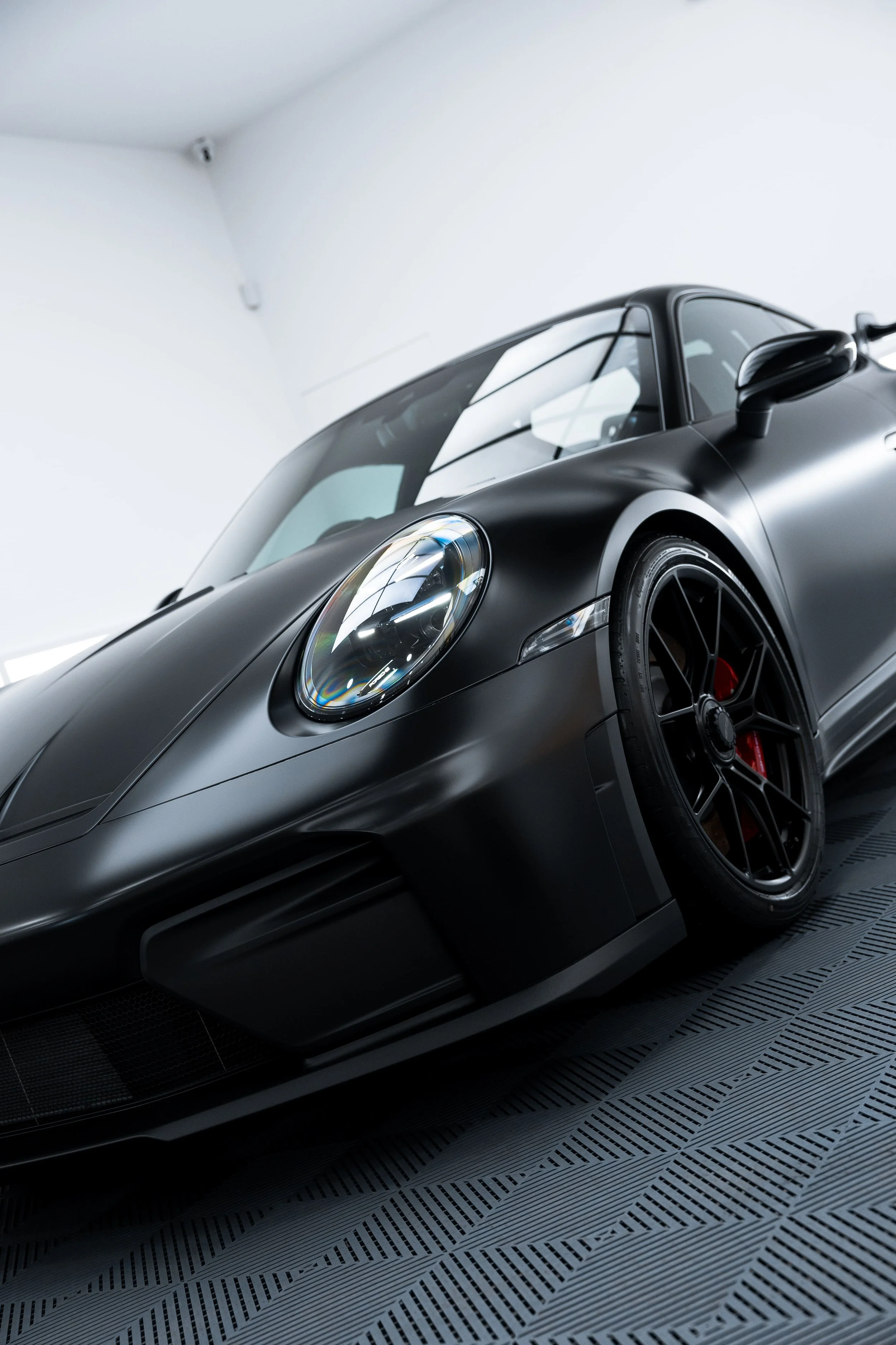 Front quarter view of black Porsche 911 GT3 with matte PPF finish and red brake calipers by ADS in Mona Vale