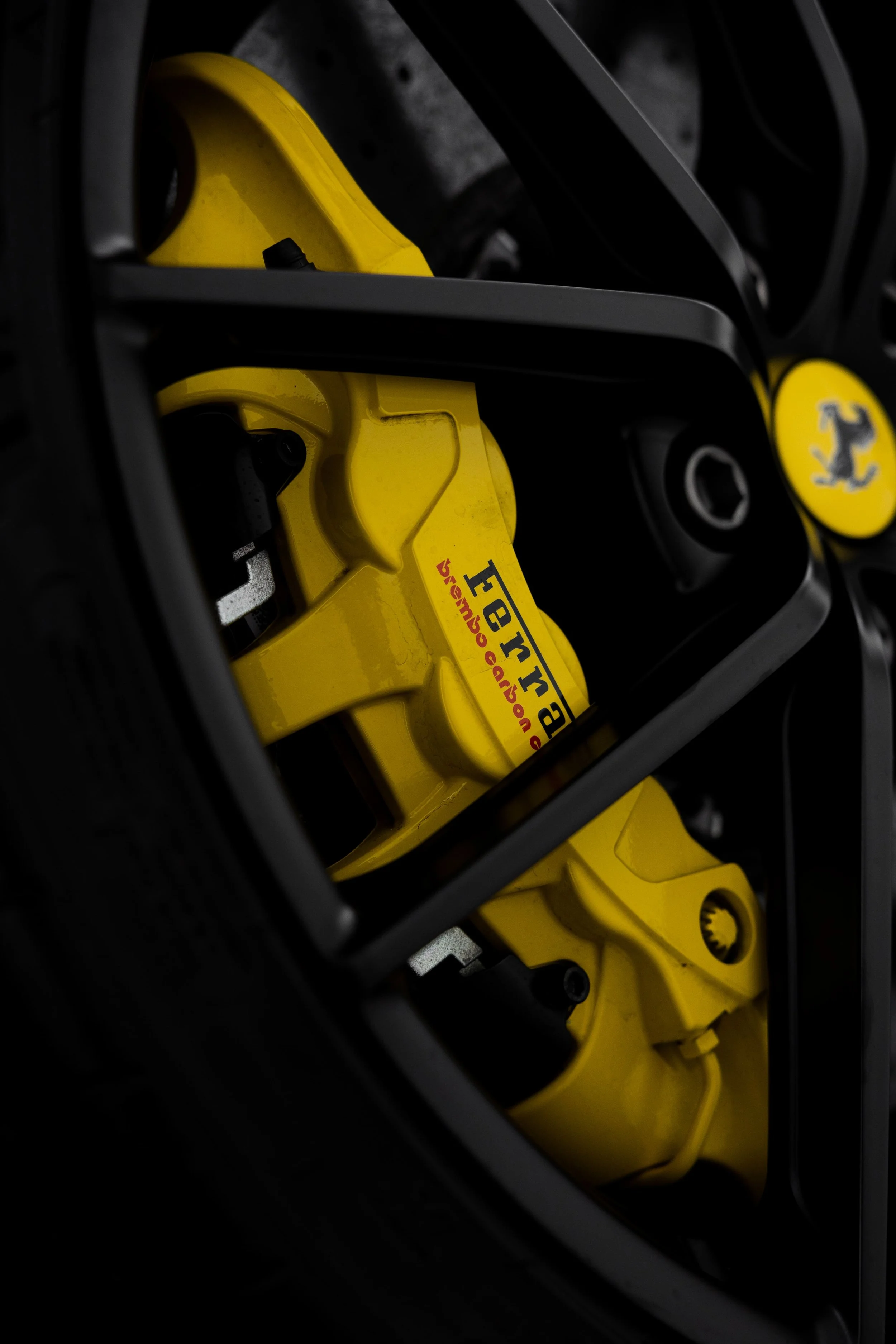 Close-up of Ferrari 488 Pista wheel showing yellow Ferrari carbon ceramic brake caliper behind black alloy spokes