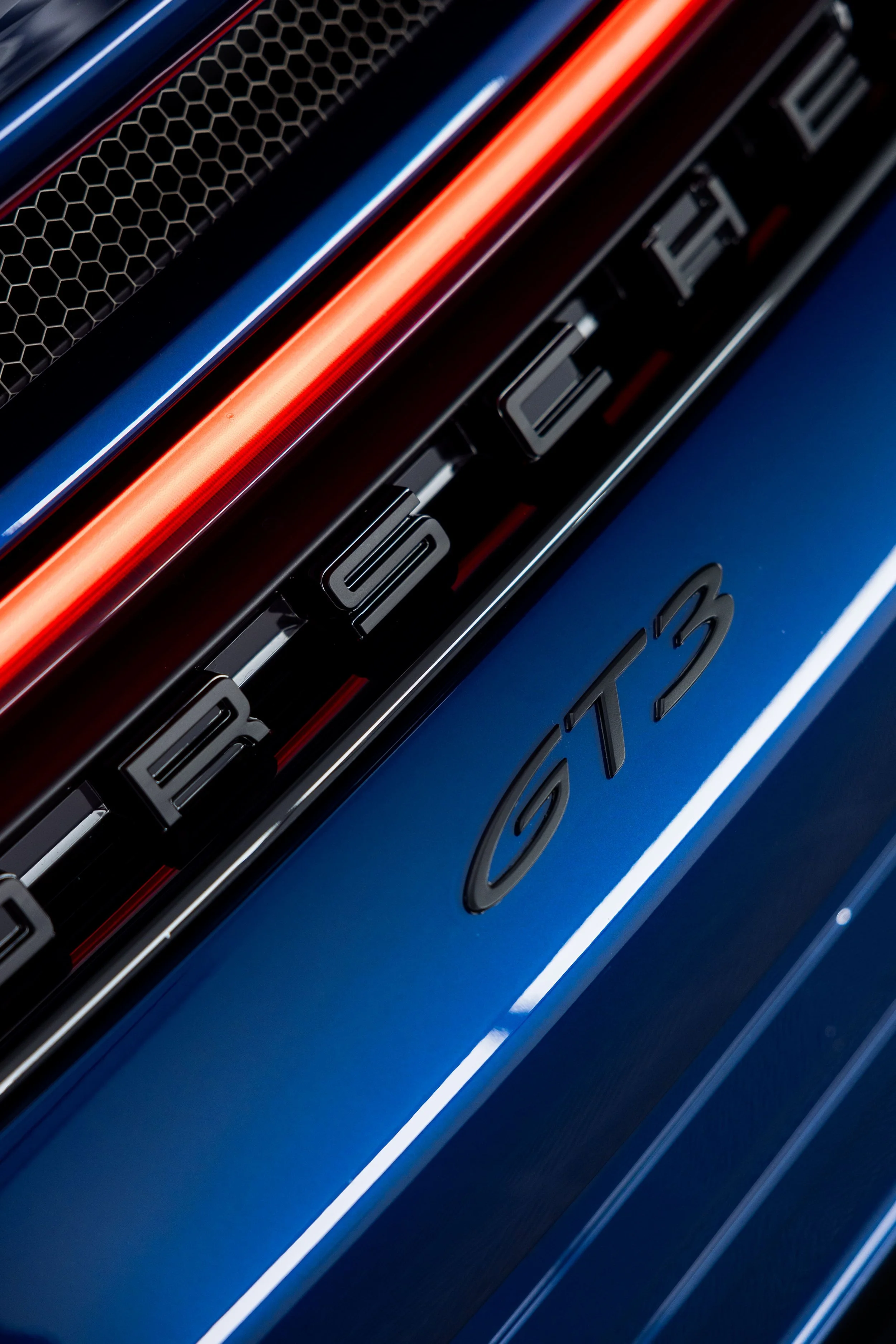 Close-up of blue Porsche 911 GT3 rear badge with illuminated LED light bar and black Porsche lettering