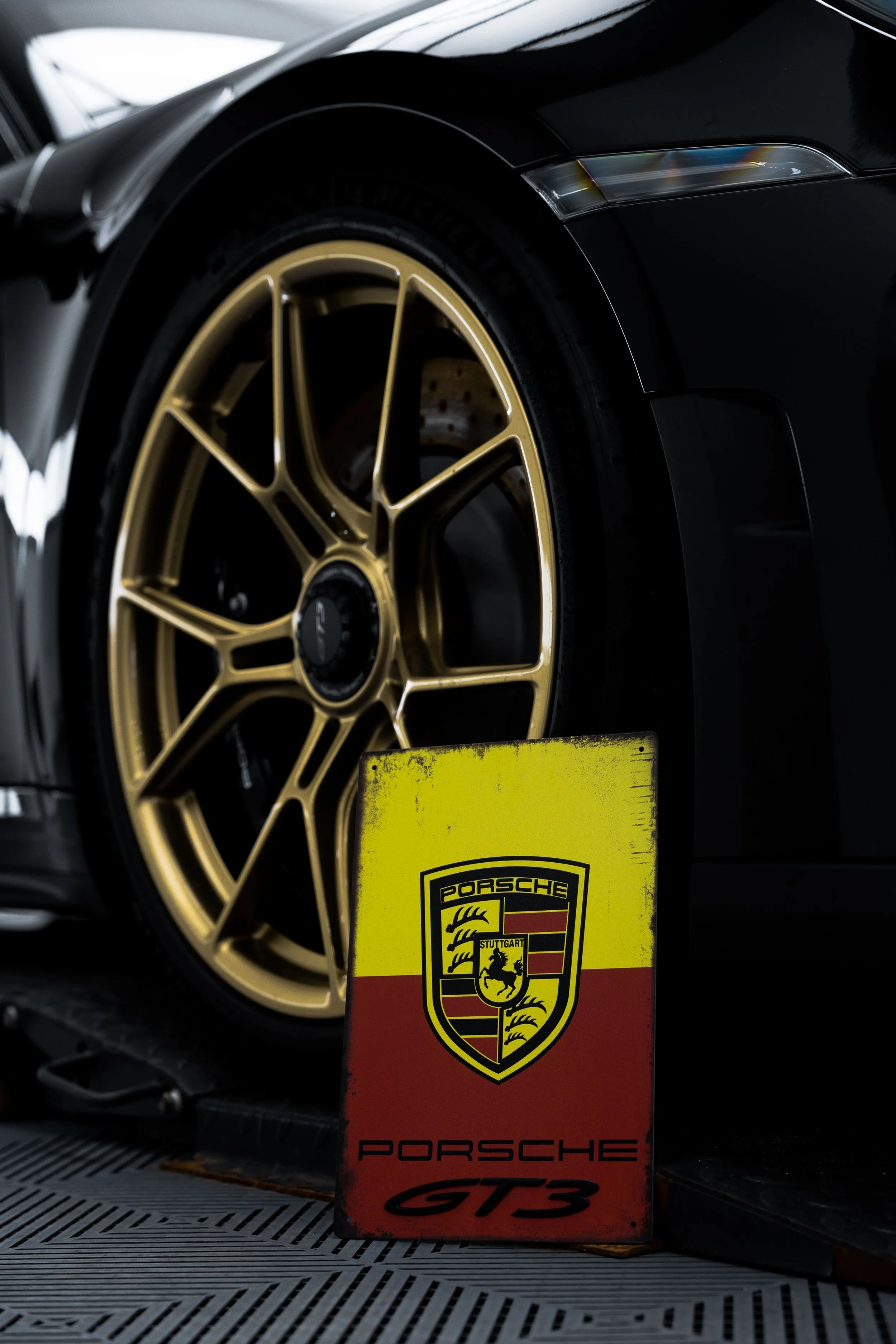 Close-up of Porsche 911 GT3 gold alloy wheel with Porsche GT3 badge in foreground, showcasing premium detailing and PPF protection by ADS