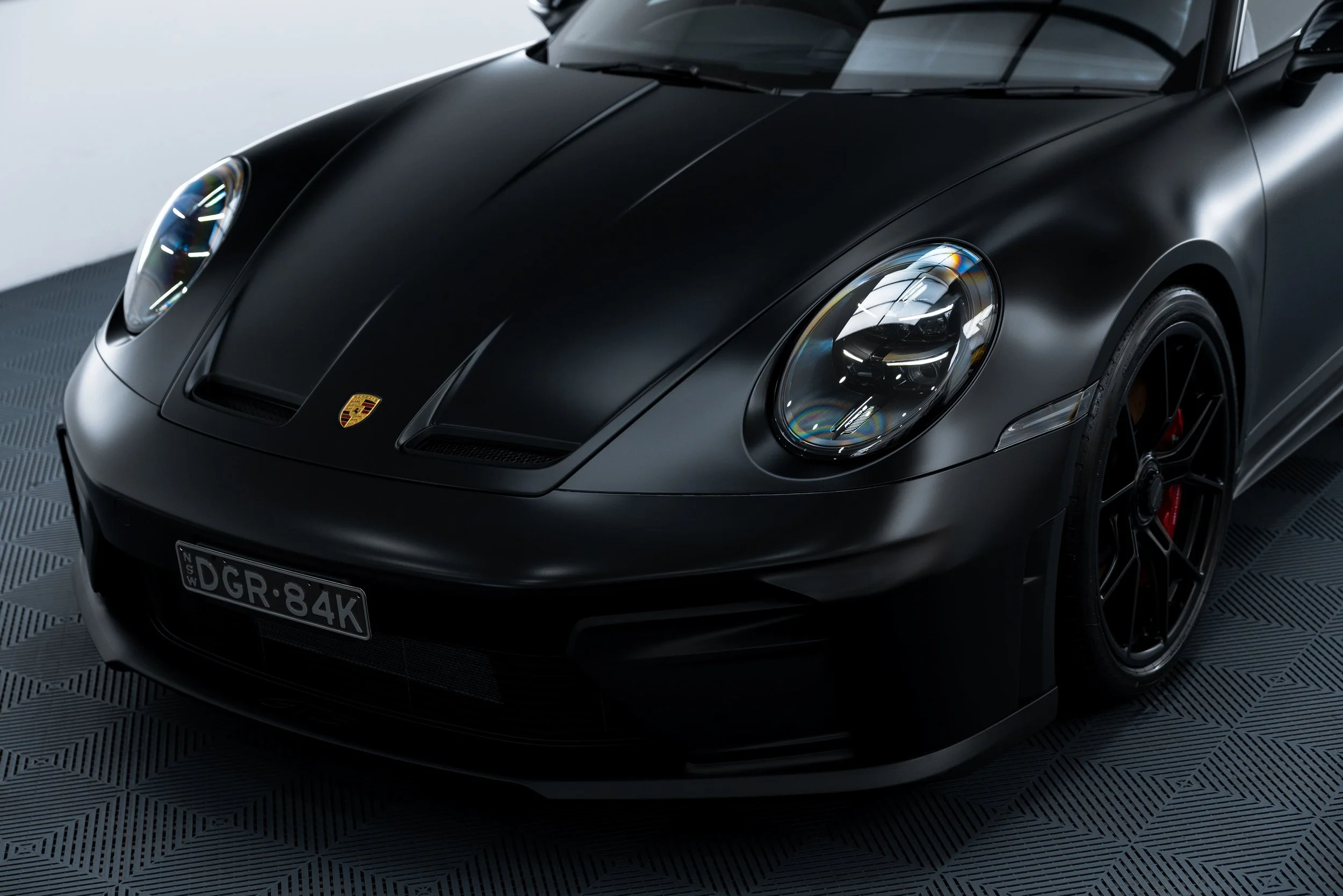 Front detail of black Porsche 911 GT3 with matte PPF finish and red brake calipers by ADS in Mona Vale