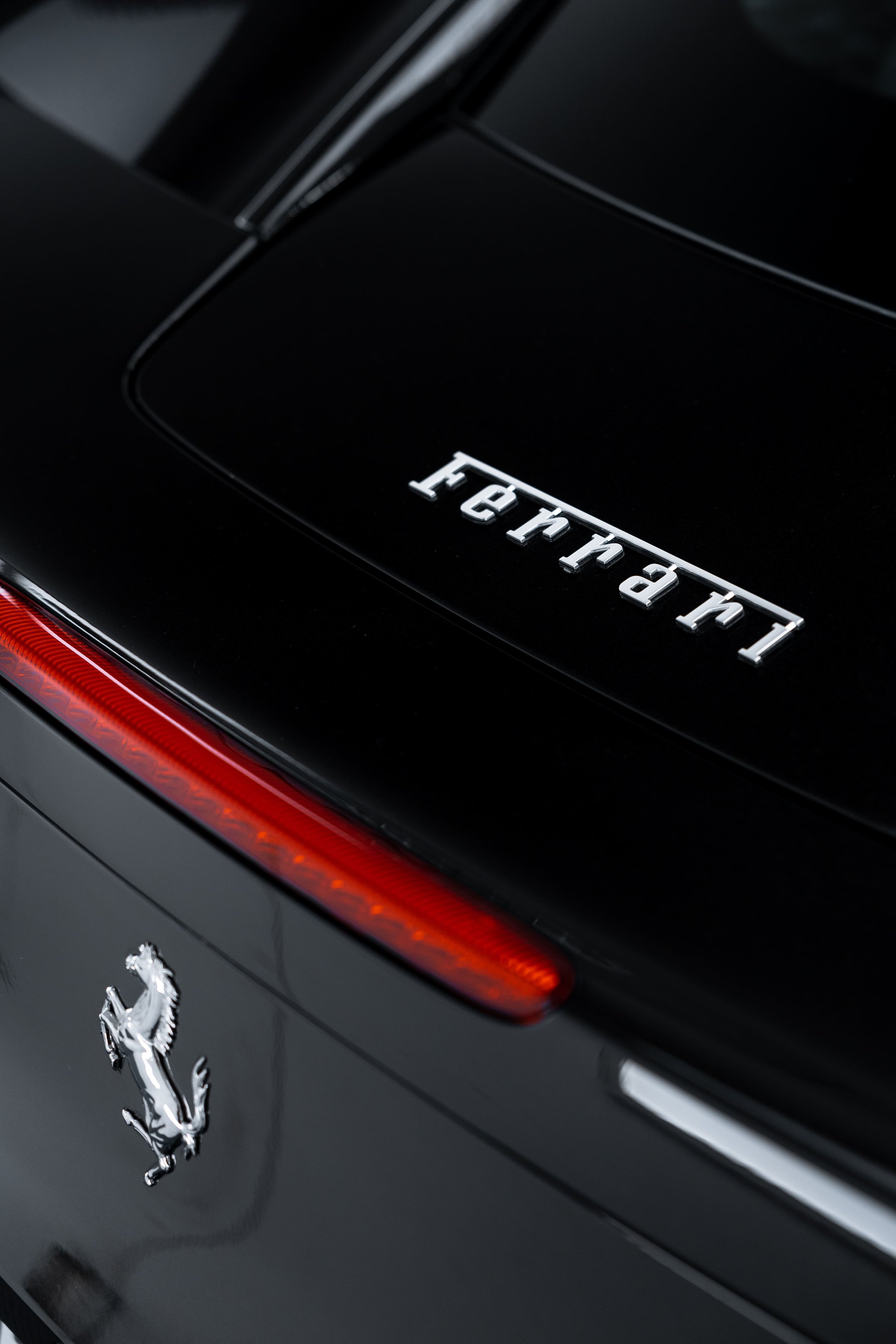 Rear detail of black Ferrari 458 with Ferrari badge and tail light protected with PPF by ADS in Mona Vale