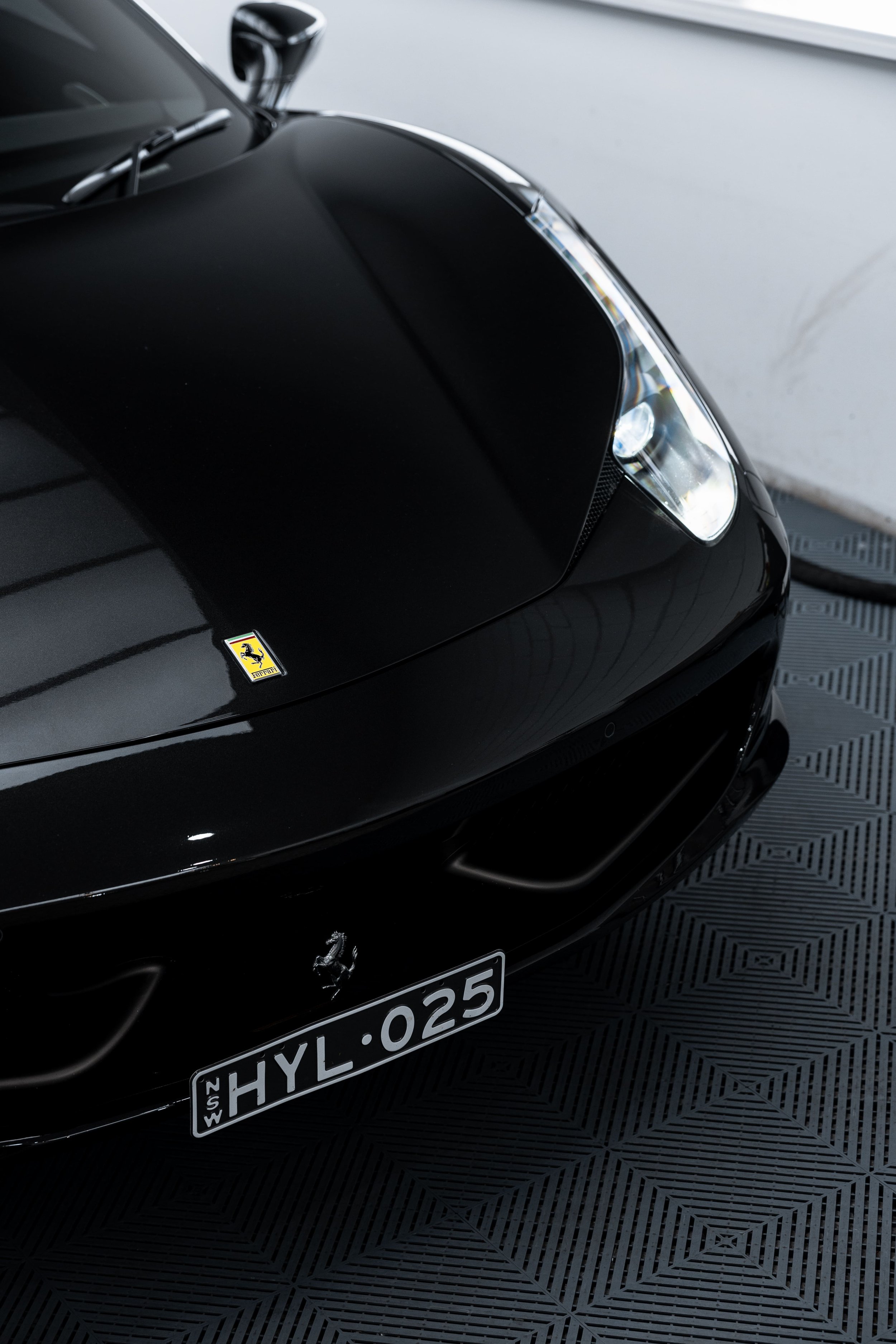 Front view detail of black Ferrari 458 with badge and NSW license plate HYL-025, finished with high-gloss detailing and PPF protection by ADS