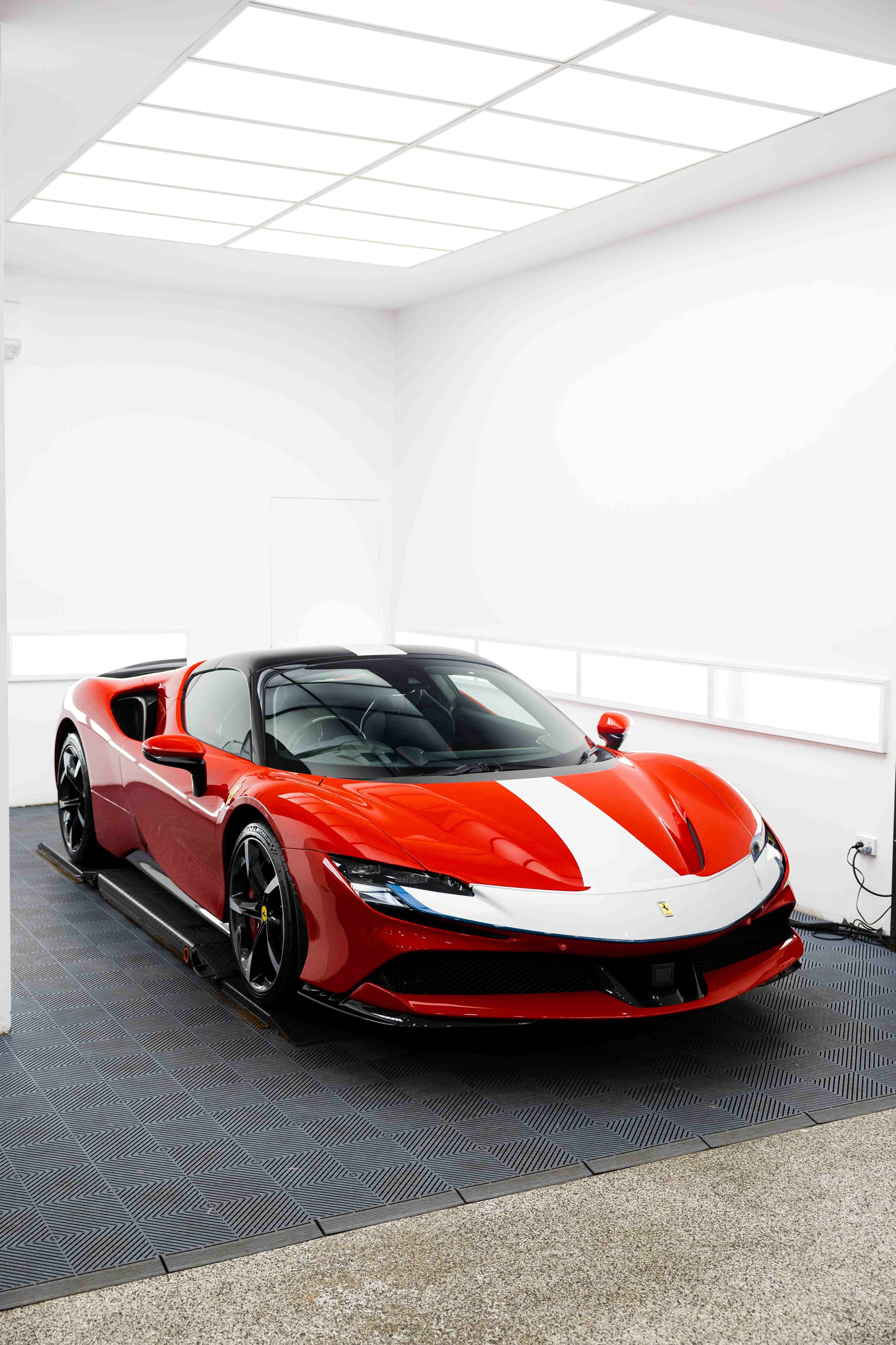 Red Ferrari SF90 Spyder front three quarter in studio with white stripe and XPEL Paint Protection Film in Mona Vale