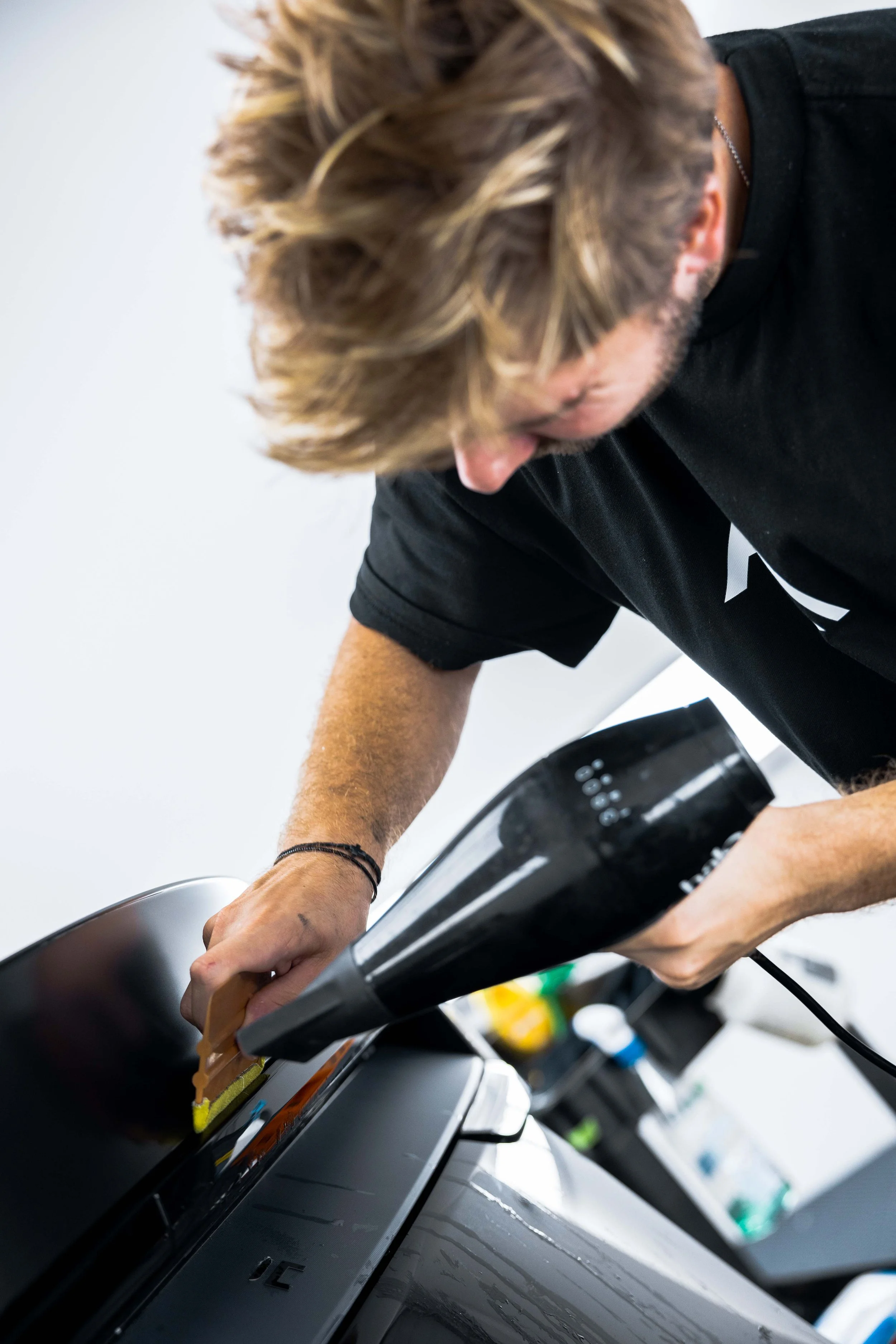ADS technician trimming XPEL Stealth Paint Protection Film with a squeegee in Mona Vale