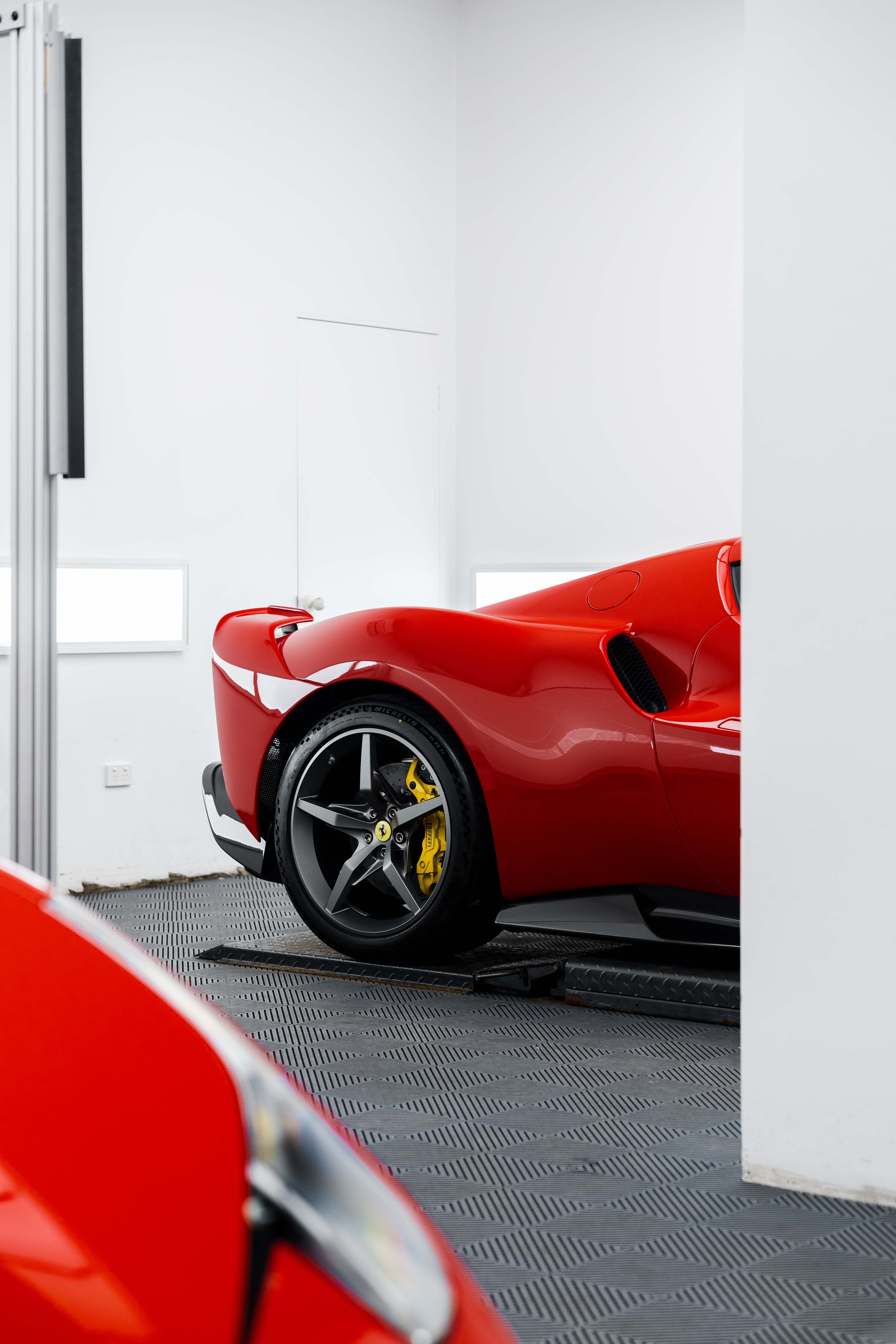 Red Ferrari 296 Speciale front wheel and yellow brake caliper in studio in Sydney