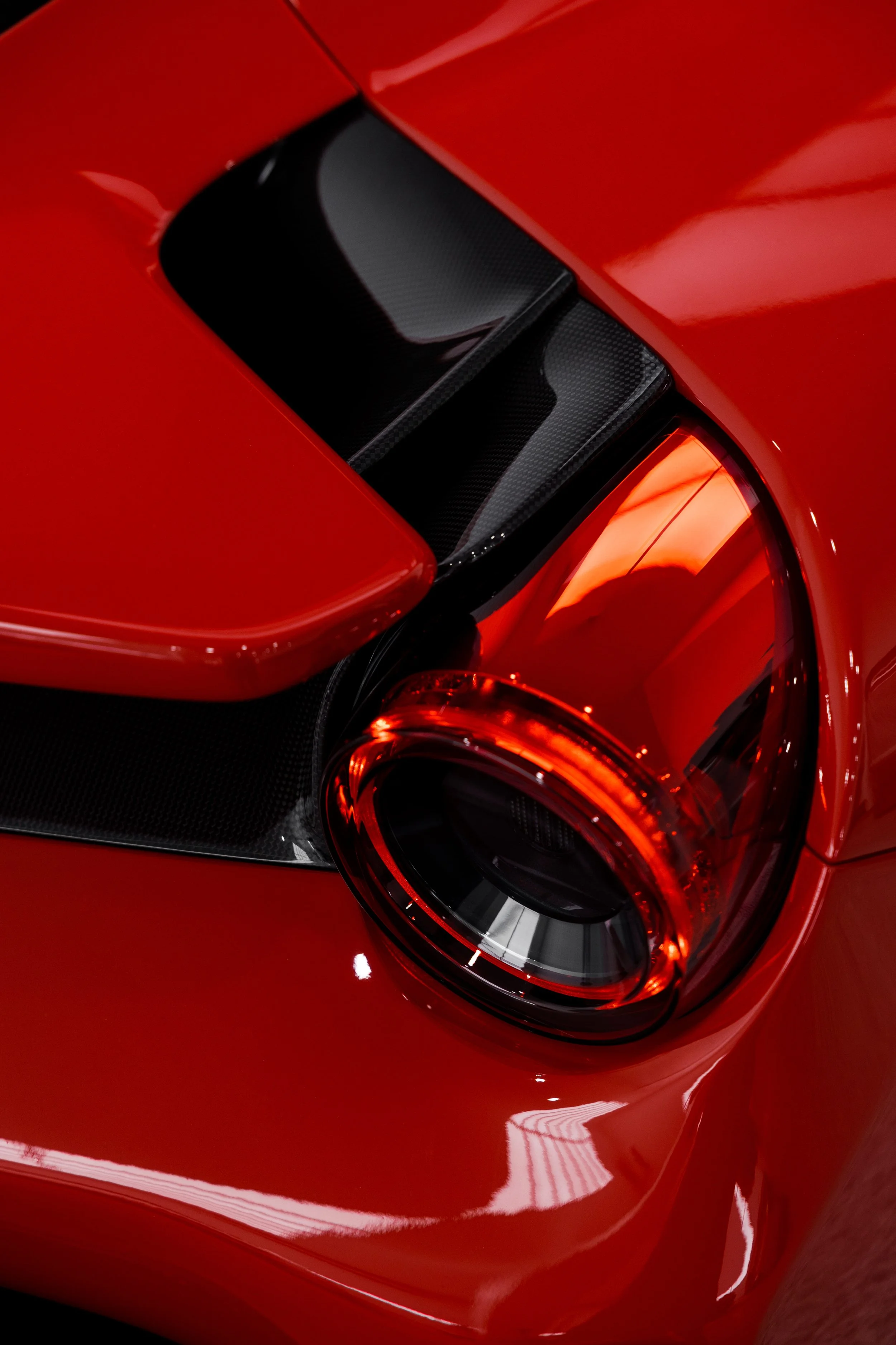 Ferrari 488 Pista rear taillight detail with carbon fibre trim and glossy red paint finish in studio