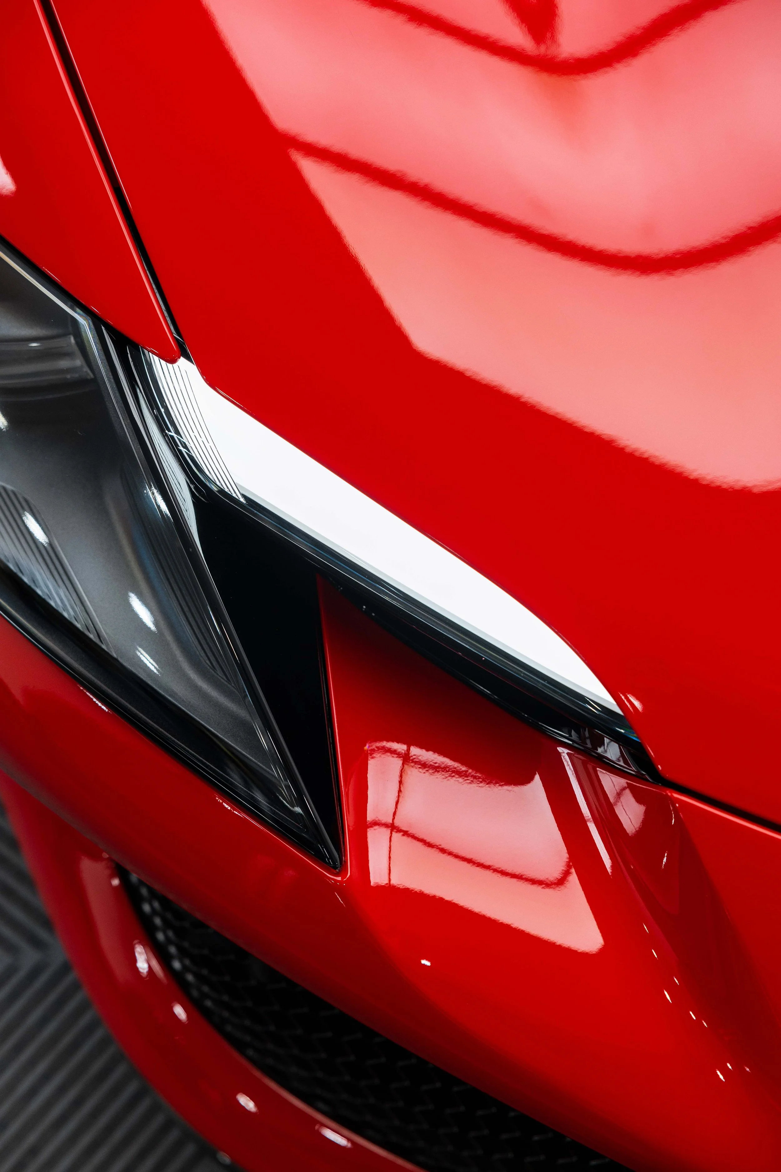 Red Ferrari 296 GTS headlight and front guard detail with XPEL Paint Protection Film in Mona Vale
