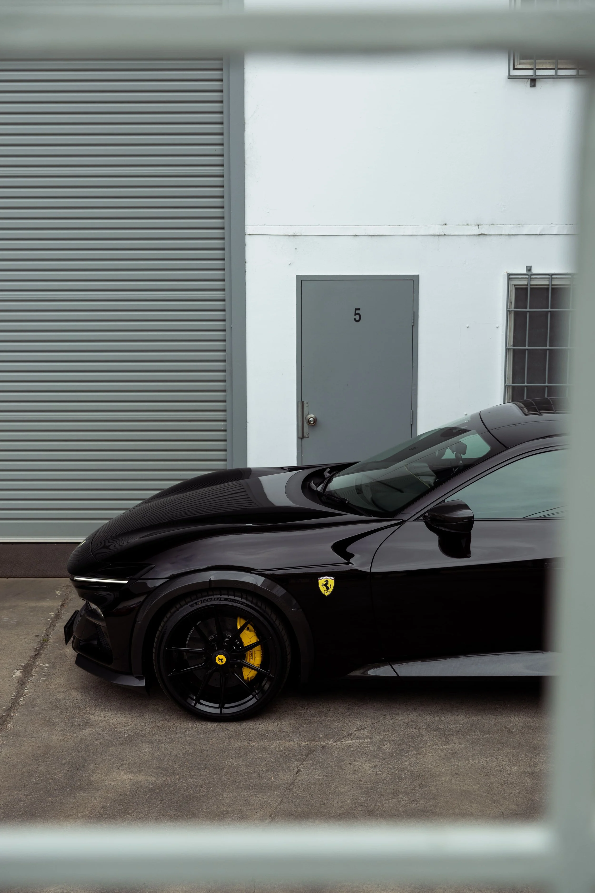 Ferrari Purosangue side profile detail in gloss black with yellow brake calipers, showcased outside ADS workshop and protected by PPF by Australian Detailing Services Sydney