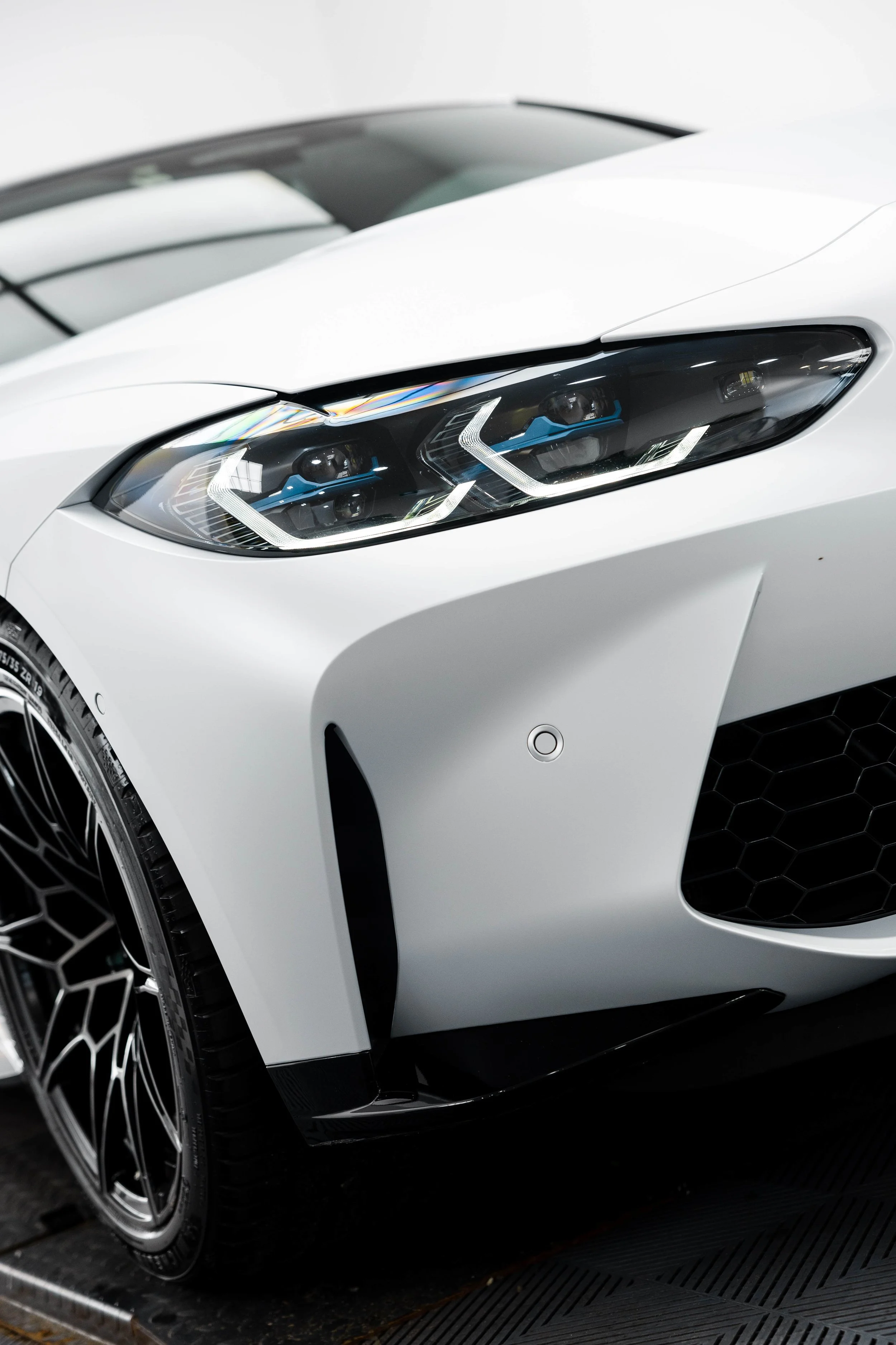 White BMW M4 Competition headlight and front wheel with XPEL Paint Protection Film in Sydney