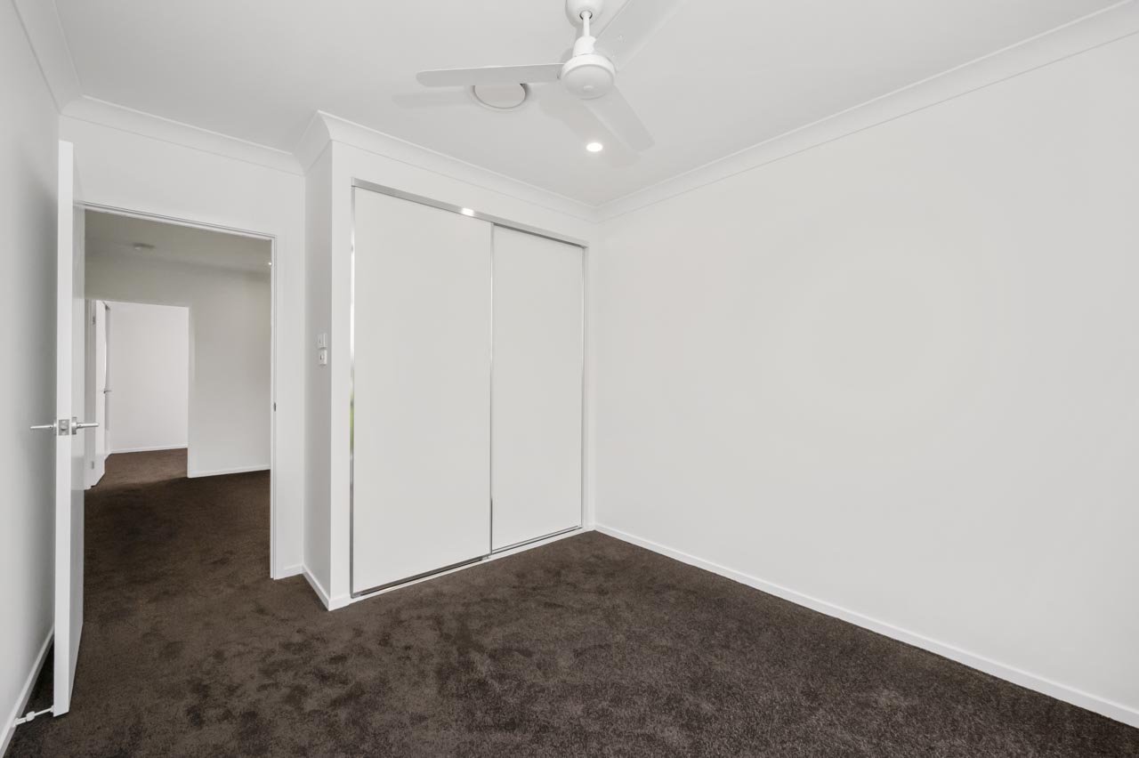 Bedroom with ceiling fan and dark chocolate brown carpet_Carnelian Projects.jpg