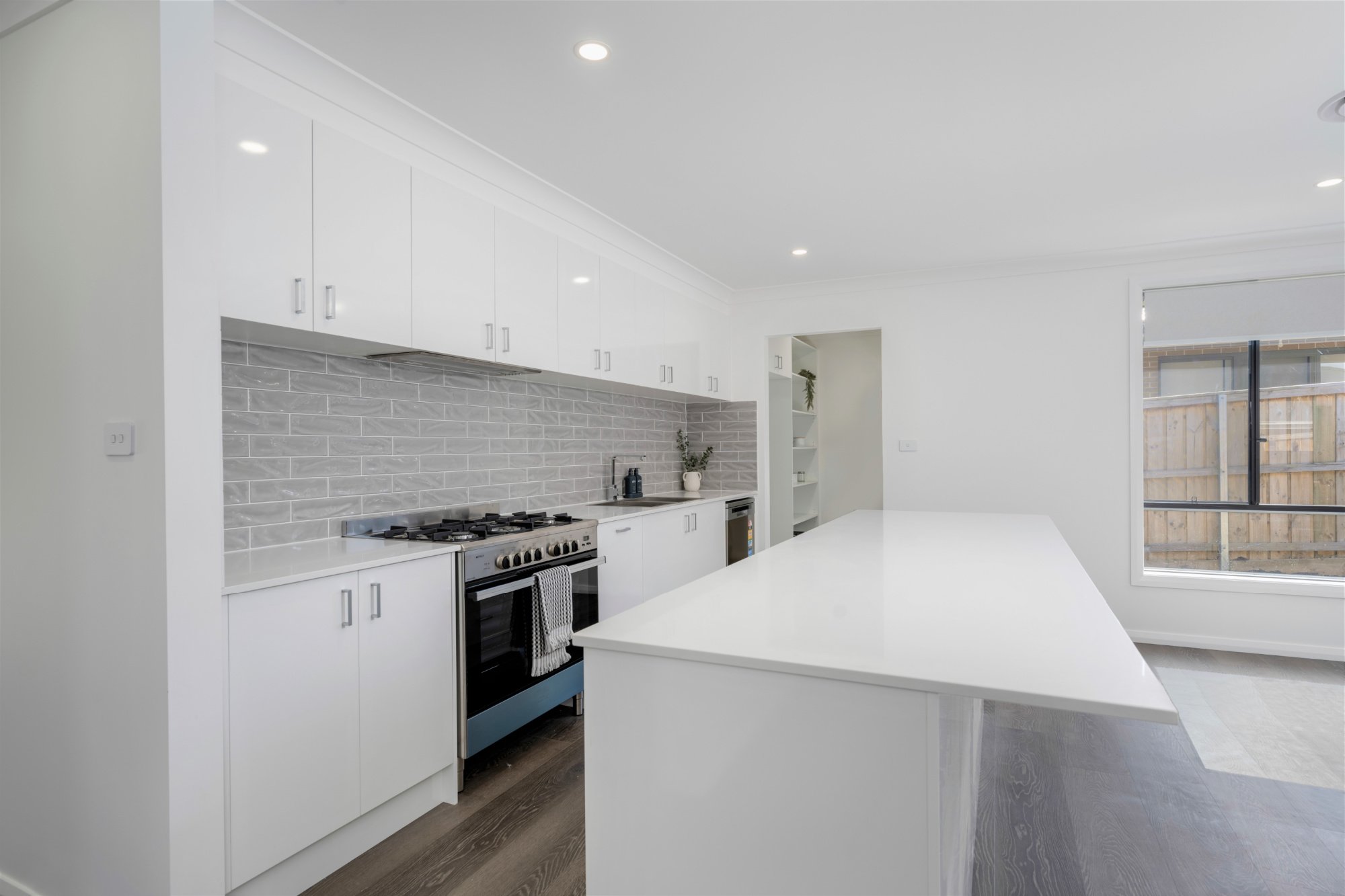 White kitchen with textured grey subway tiles splashback and white stone bench_Carnelian Projects.jpg